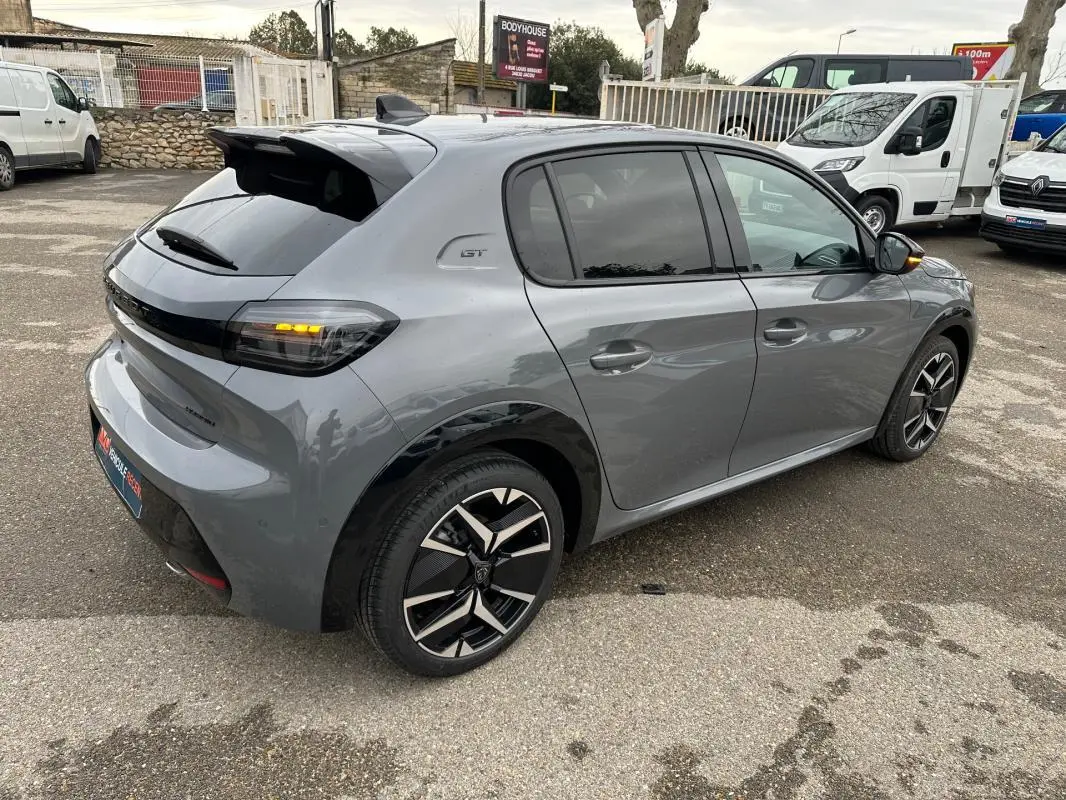 Vue 3/4 arrière droite d'une Peugeot 208 Hybrid 110 e-DCS6 GT gris avec jantes alliage 17 pouces et feux arrière allumés.