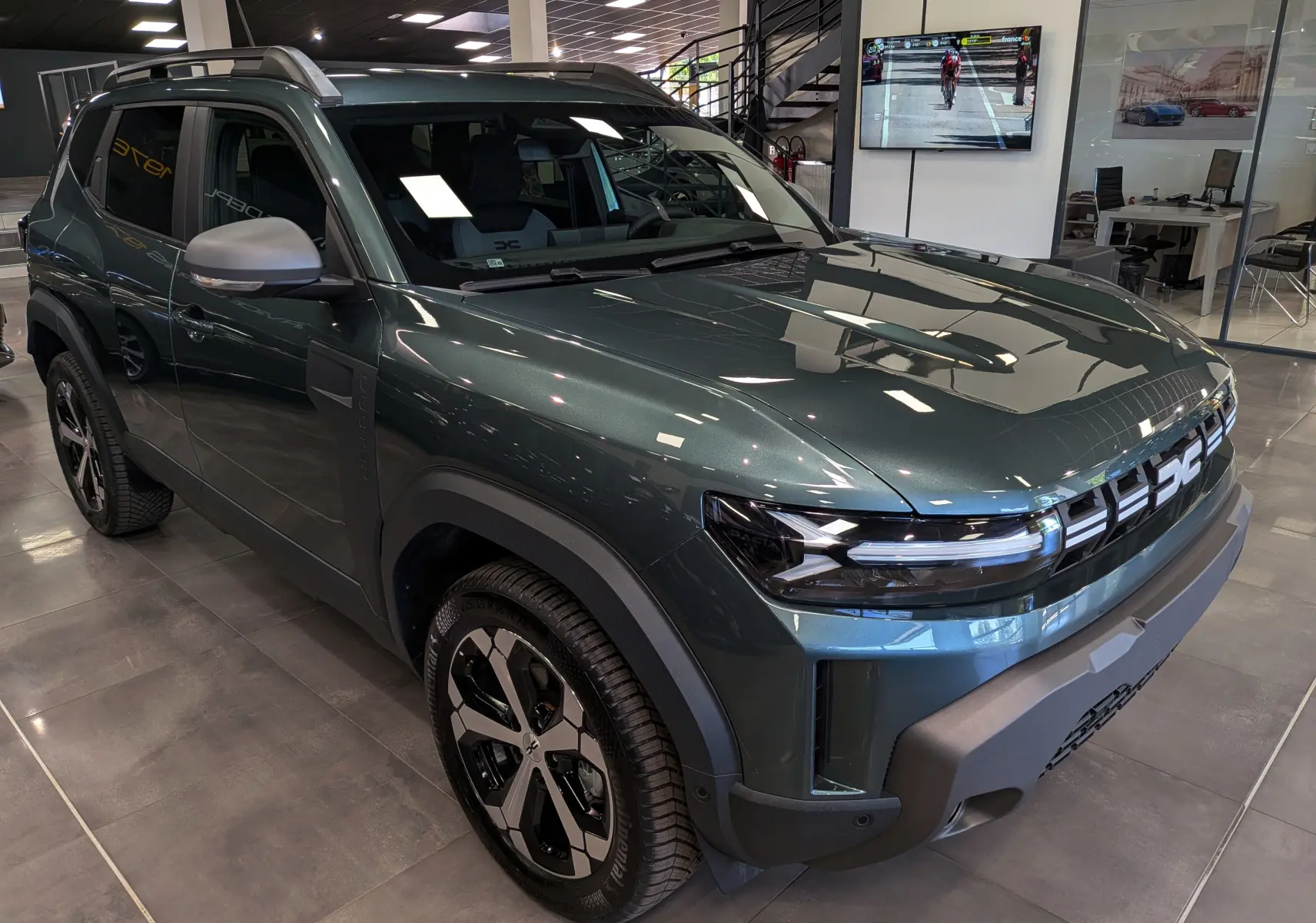 Vue 3/4 avant droite du Dacia Duster Hybrid-G 150 CH 4x4 en Vert Cèdre avec jantes bi-ton et calandre moderne.