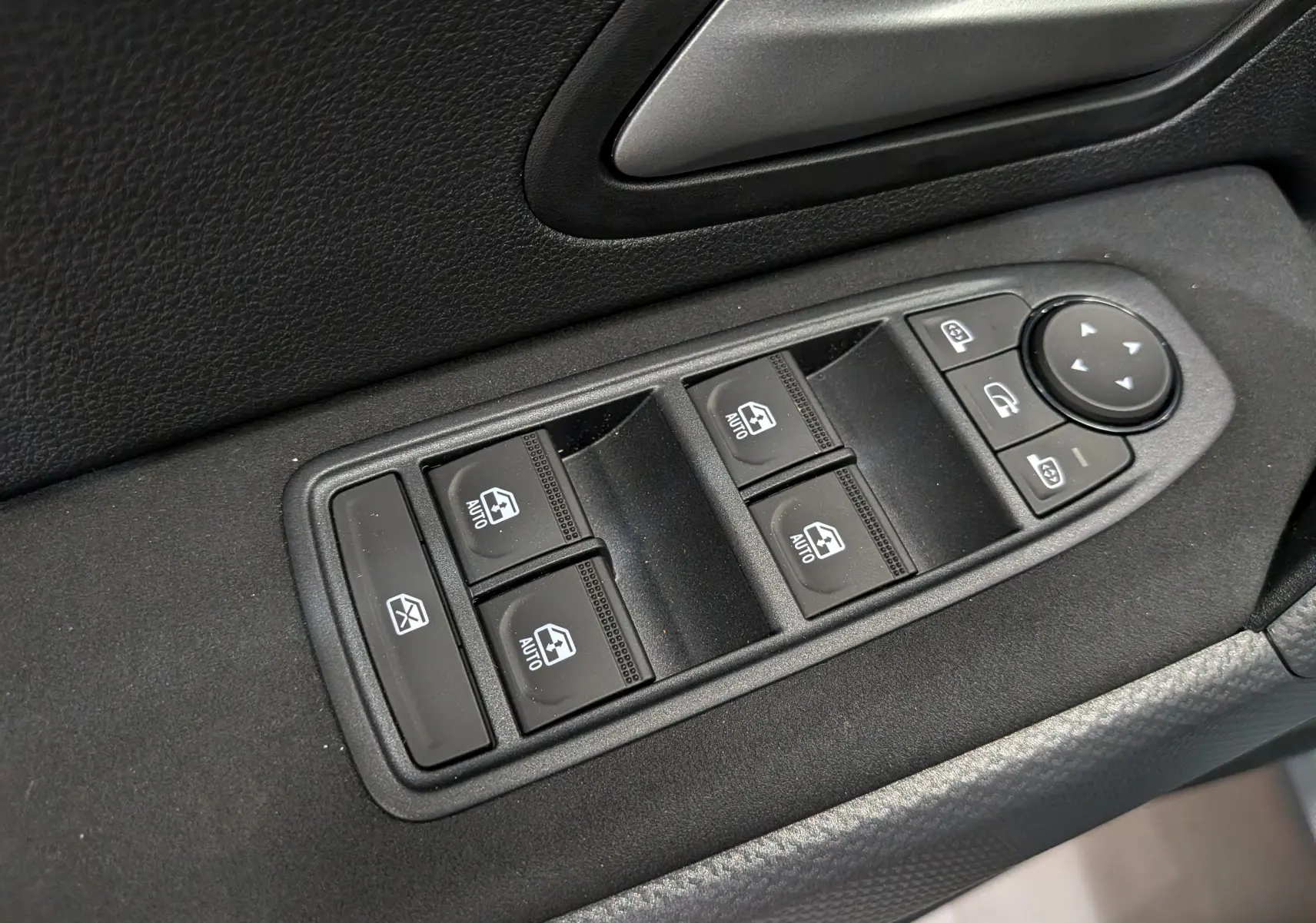 Gros plan sur les commandes des vitres électriques et rétroviseurs côté conducteur du Dacia Duster Hybrid-G 150 CH 4x4 2026.