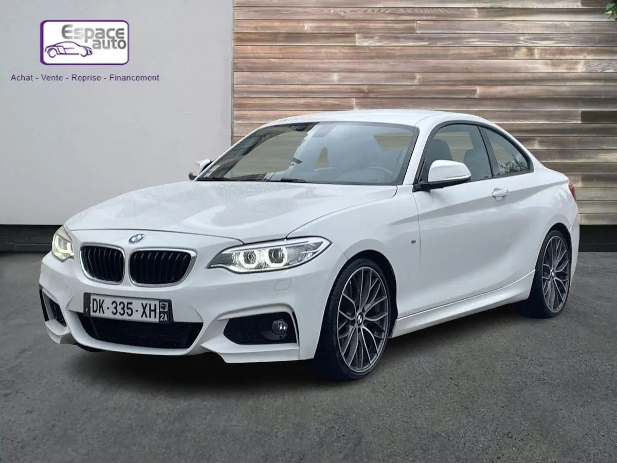 BMW Série 2 Coupé 220d M Sport blanc en 3/4 avant droit, avec phares allumés et jantes alliage distinctives.