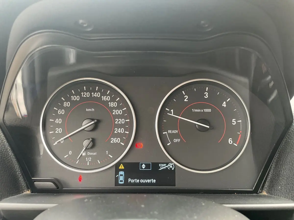 Vue rapprochée du tableau de bord de la BMW Série 2 Coupé F22 blanche, affichant le compteur et le témoin "Porte ouverte".