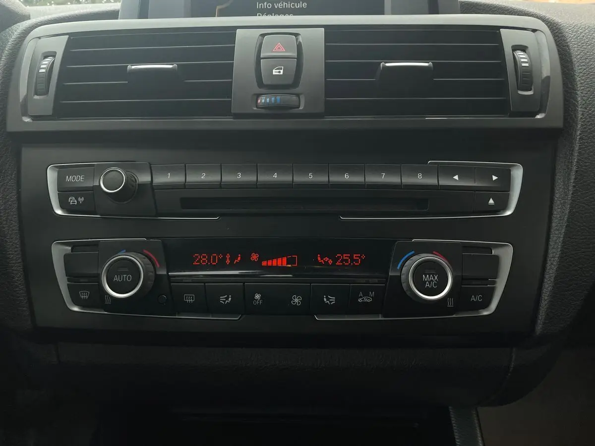 Vue rapprochée du tableau de bord noir de la BMW Série 2 Coupé F22 blanc, avec commandes climatisation et radio visibles.