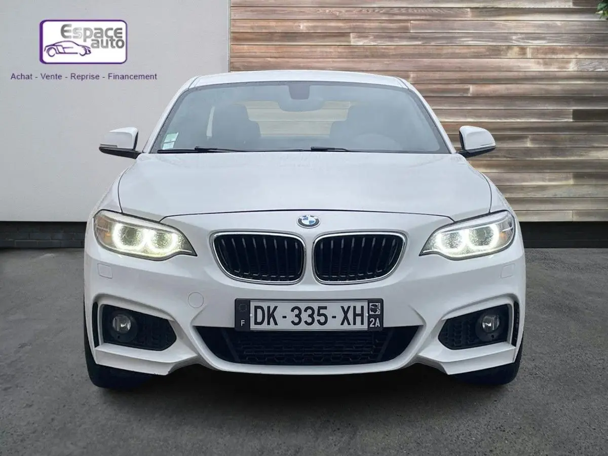 Vue frontale d'une BMW Série 2 Coupé F22 blanche avec phares allumés et calandre M Sport distinctive.