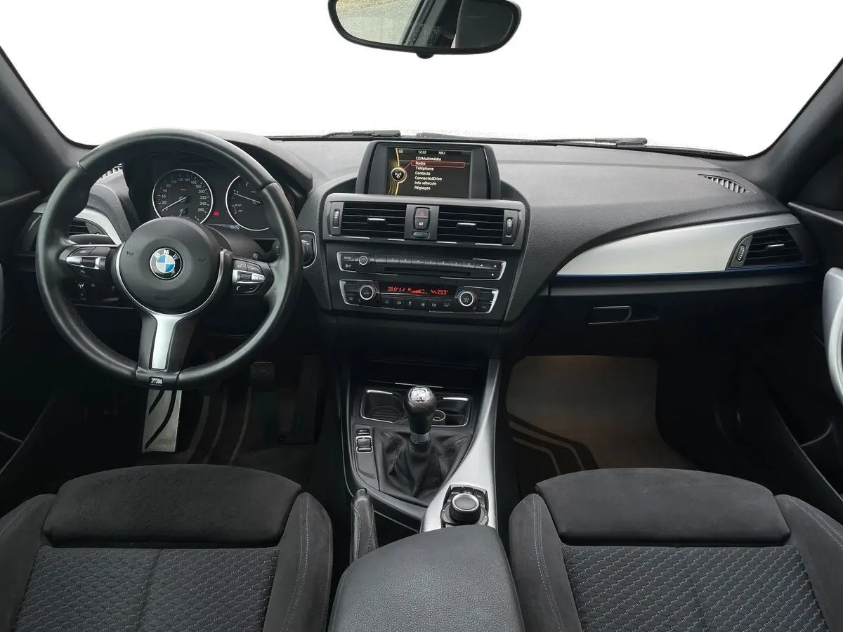 Vue intérieure avant du tableau de bord et volant M Sport d'une BMW Série 2 Coupé F22 blanche de 2014 avec boîte manuelle.