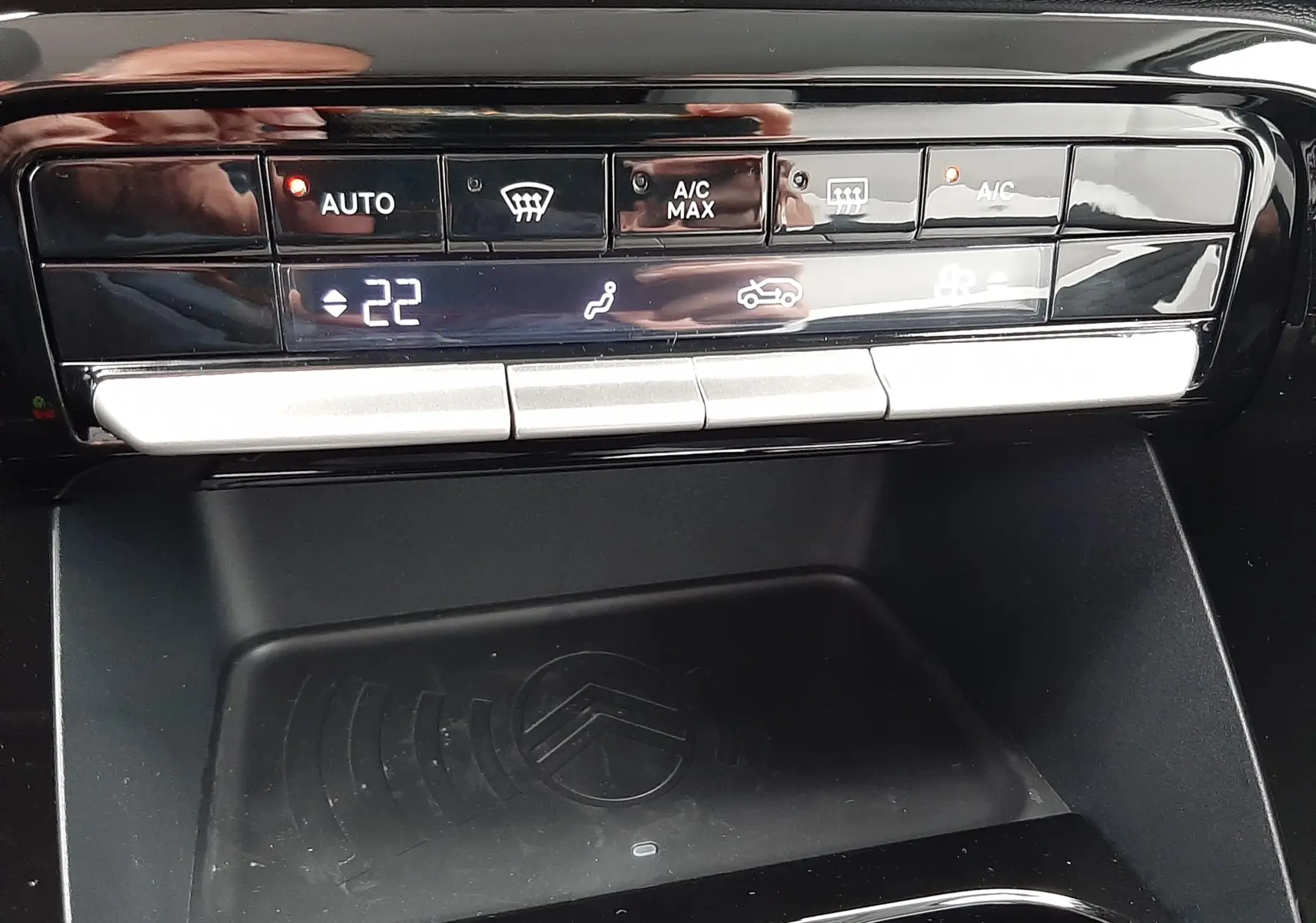 Détail de la console centrale noire du Citroën C3 Aircross 1.2 Hybrid 145 gris Mercury, avec commandes climatisation et zone de recharge.