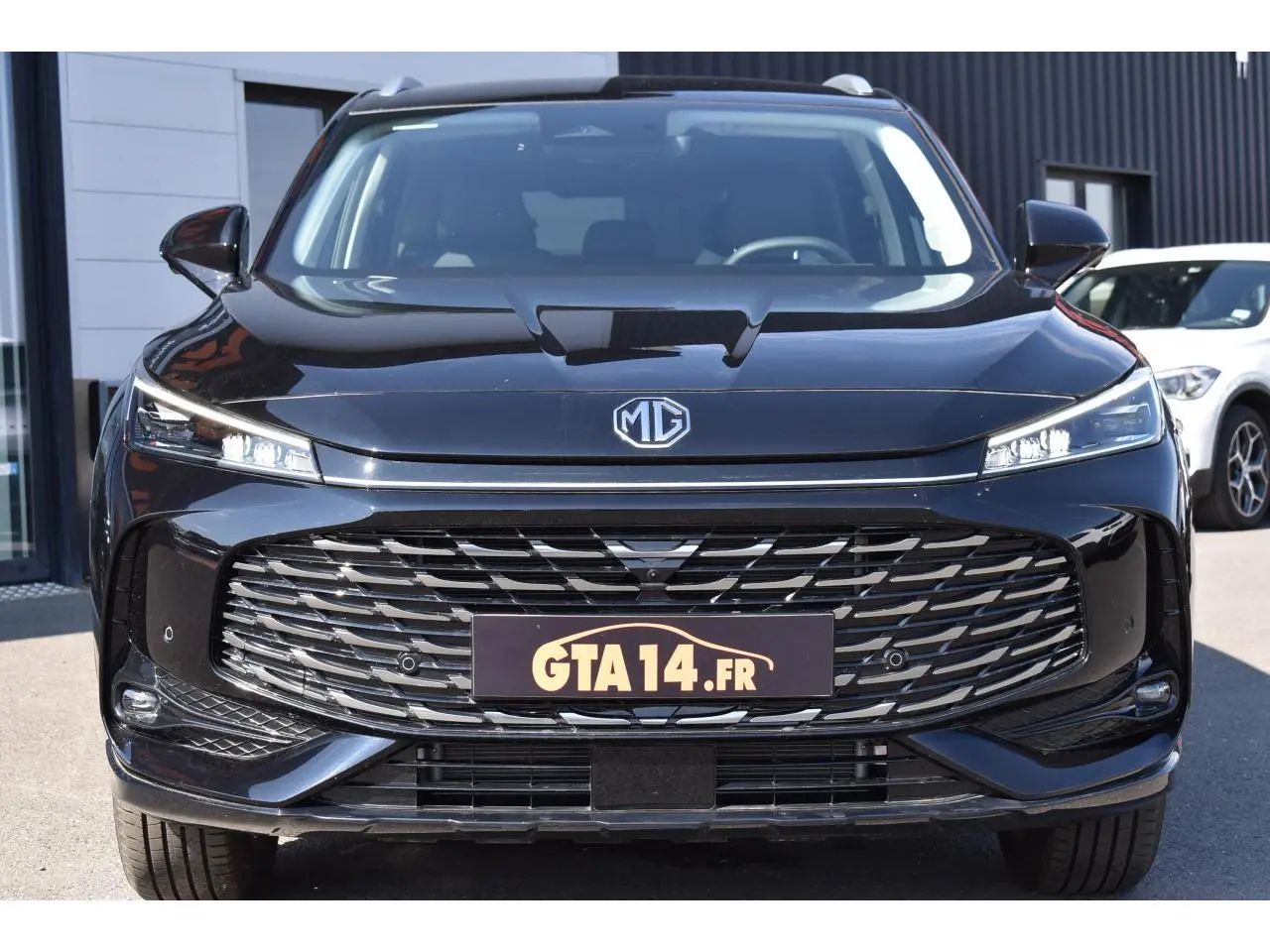 Vue frontale d’un MG MOTOR EHS 1.5 Hybrid+ noir métallisé avec calandre large et phares LED fins.