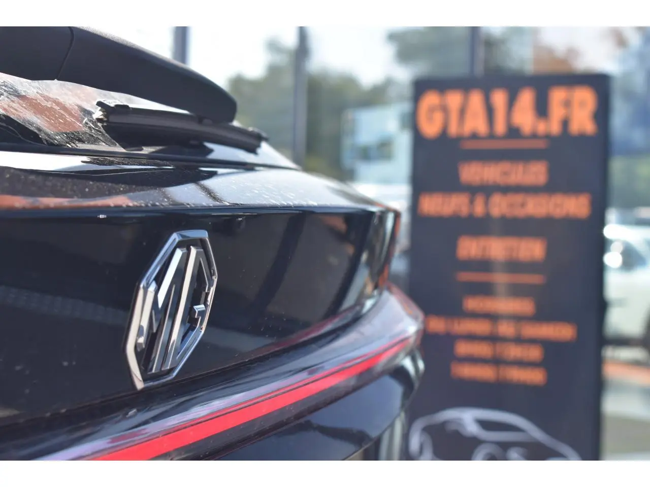 Gros plan sur l'arrière noir métallisé du MG EHS 1.5 Hybrid+ 224 ch Luxury avec logo MG et feu arrière fin rouge.