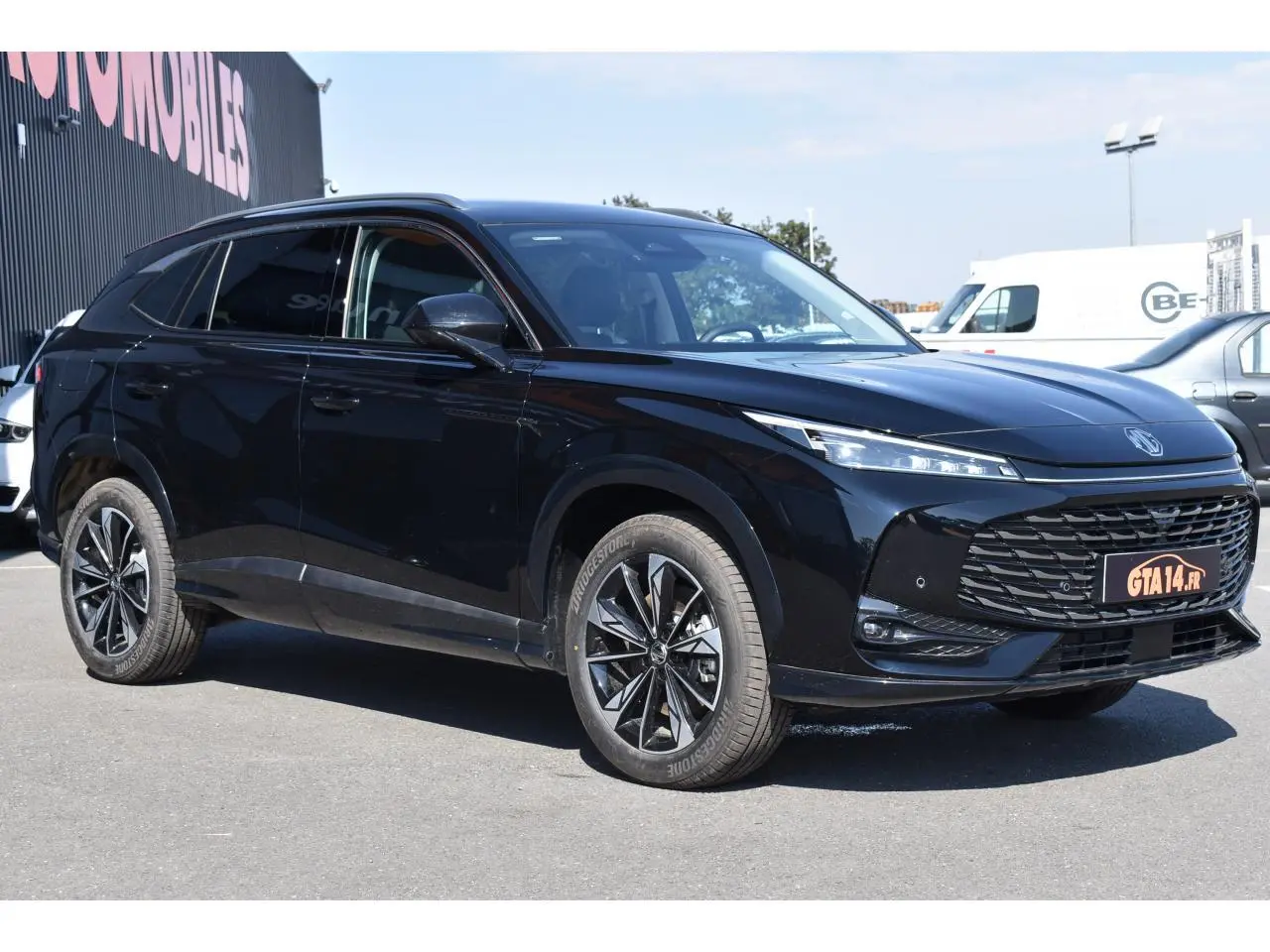 MG Motor EHS 1.5 Hybrid+ noir métallisé en 3/4 avant droit avec jantes alliage et calandre imposante.