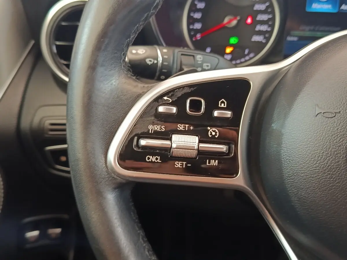 Gros plan sur la partie gauche du volant cuir noir d’un Mercedes GLC 300 hybride, avec commandes de régulateur de vitesse.