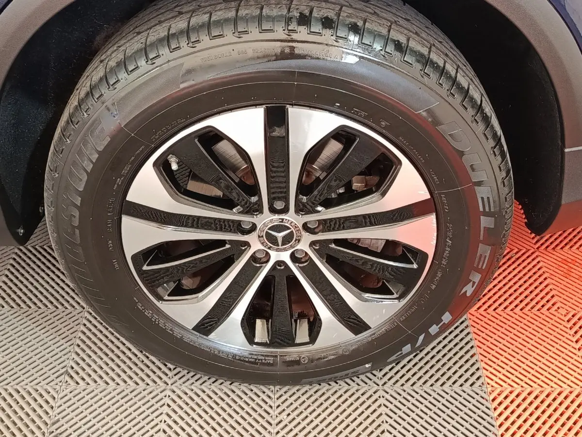 Gros plan sur la roue avant droite du Mercedes GLC bleu, jante alliage bicolore et pneu Bridgestone Dueler.
