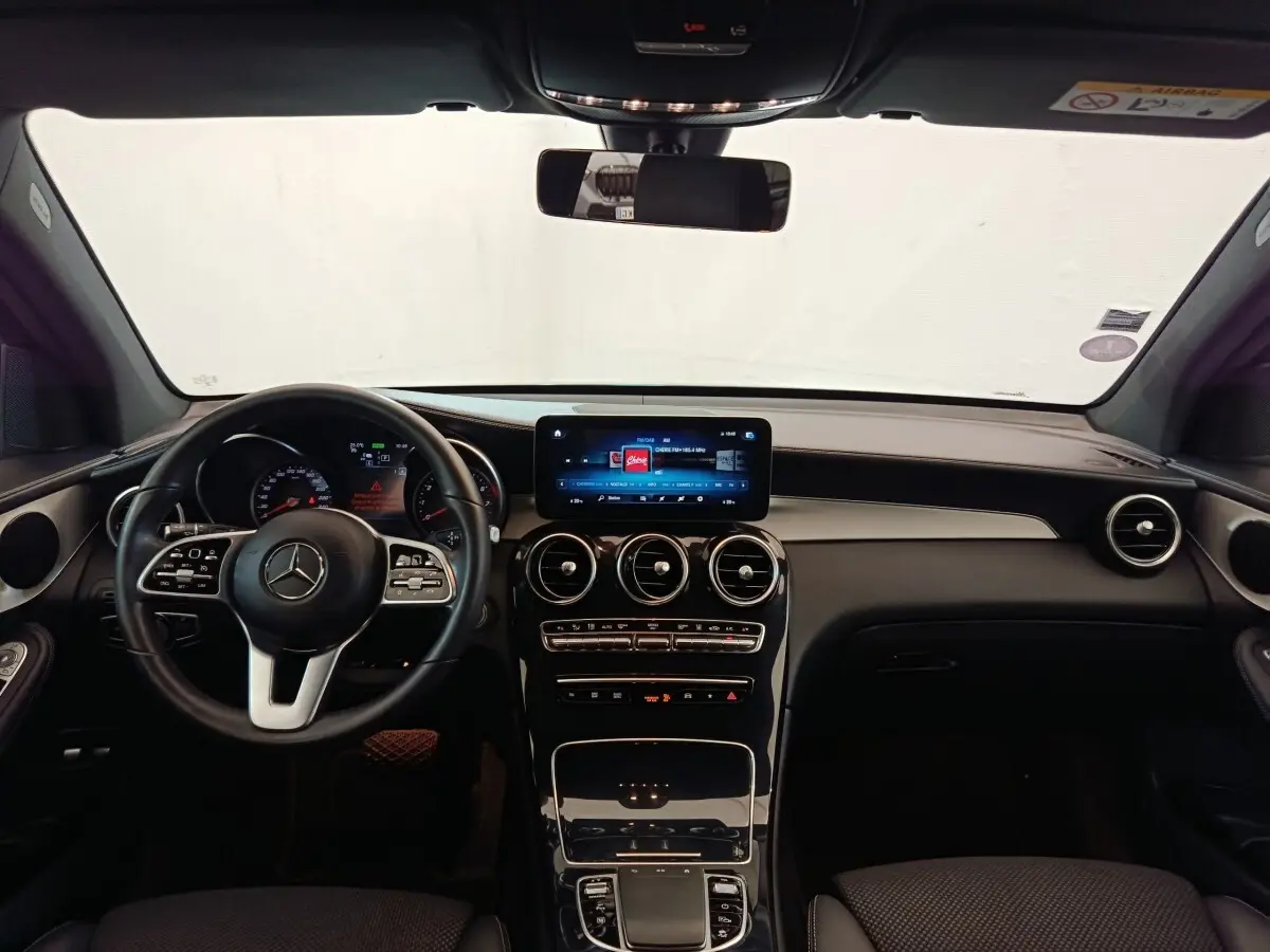 Vue intérieure avant du Mercedes GLC 300 DE Business Line 2022, tableau de bord noir avec écran tactile central et volant cuir.