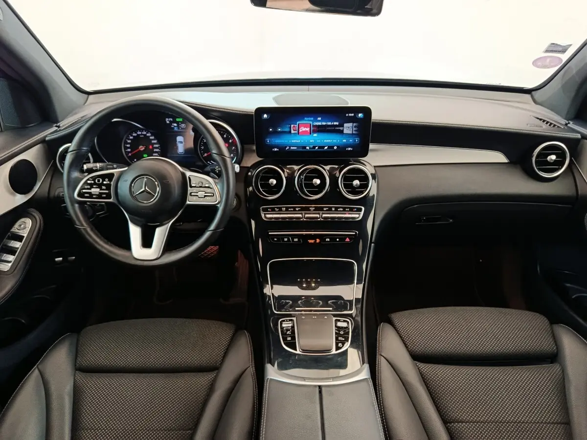 Vue intérieure avant du Mercedes GLC 300 hybride rechargeable 2022, tableau de bord noir avec écran tactile central lumineux.
