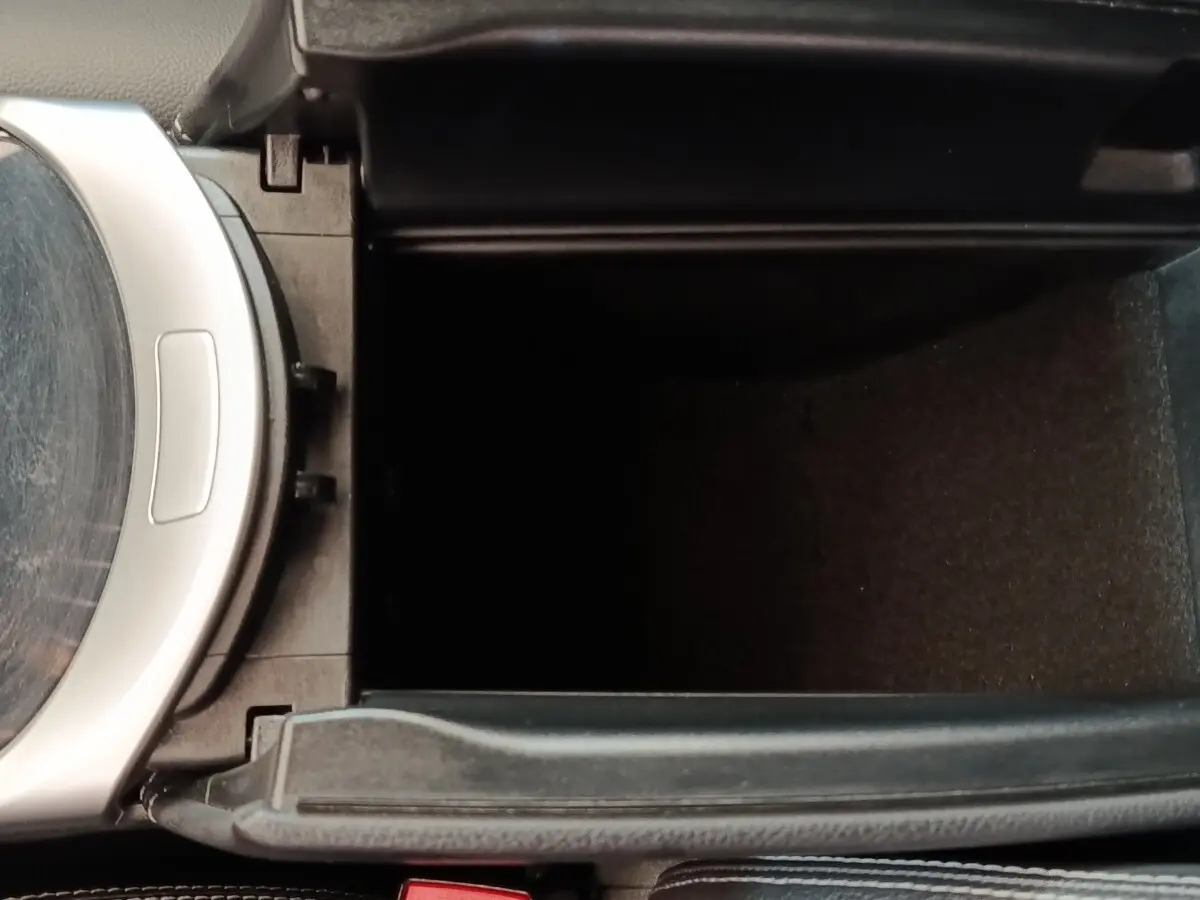 Vue rapprochée de la console centrale ouverte du Mercedes GLC bleu, montrant le compartiment de rangement intérieur.
