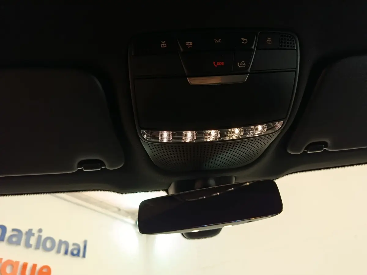 Vue intérieure en contre-plongée du plafonnier noir avec commandes et rétroviseur intérieur du Mercedes GLC 300 hybride 2022.