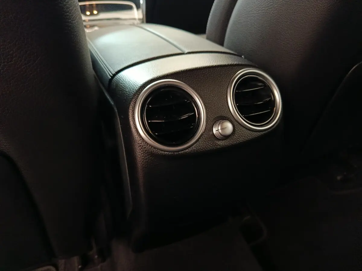 Gros plan sur les aérateurs arrière noirs avec cerclage argenté dans l’habitacle du Mercedes GLC 300 hybride rechargeable bleu.