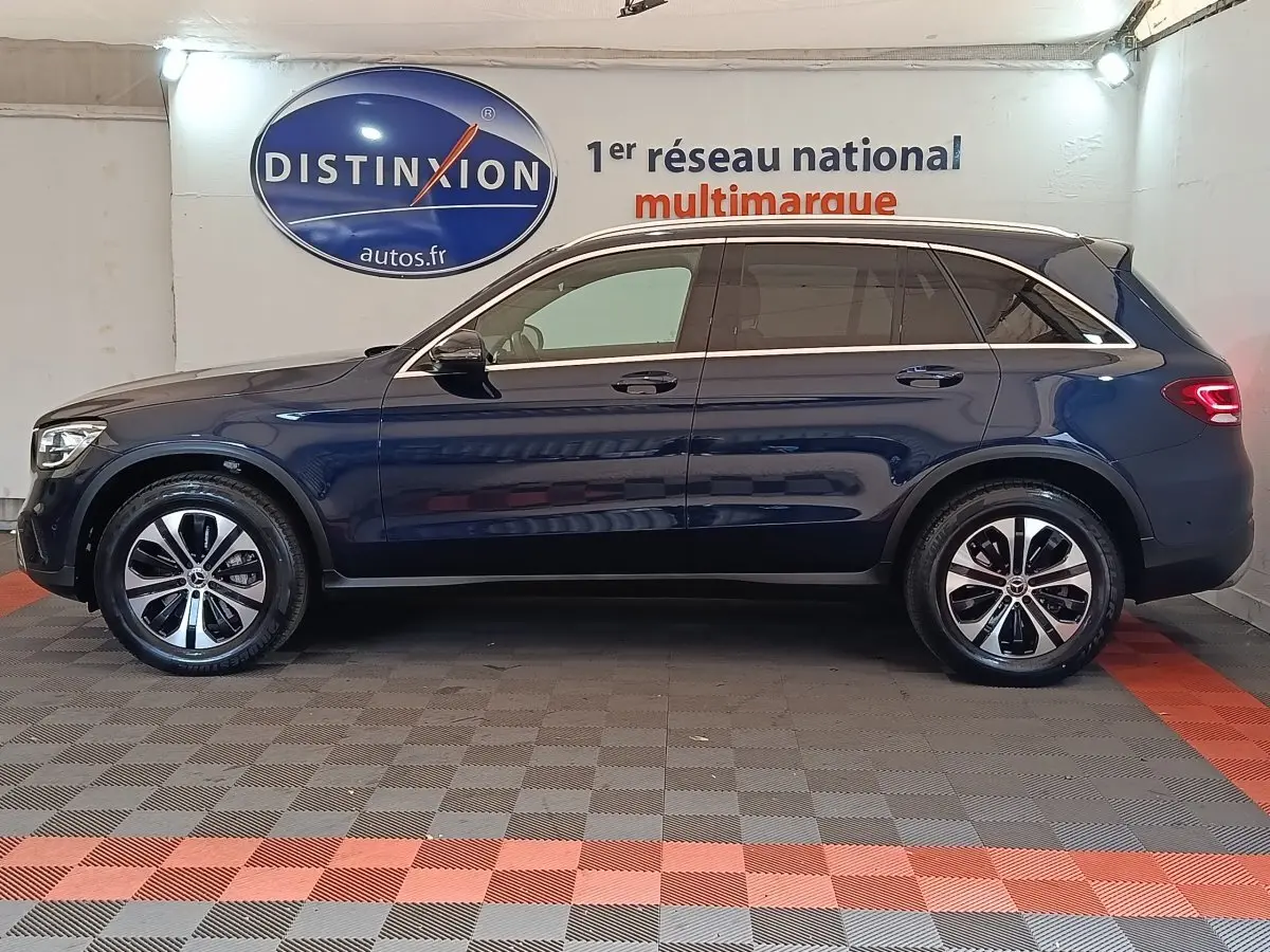 Profil droit d'un Mercedes GLC 300 DE Business Line 4MATIC bleu, avec jantes alliage et toit chromé visible en intérieur showroom.