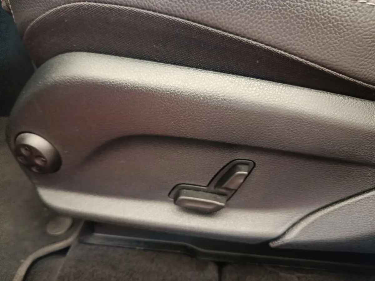 Commande de réglage électrique du siège avant en cuir marron d’un Mercedes GLC bleu, vue latérale rapprochée.