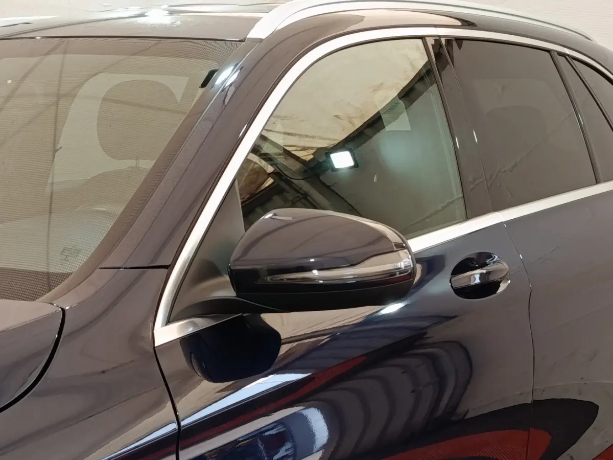 Détail du côté gauche d’un Mercedes GLC bleu avec rétroviseur et poignée de porte visibles.