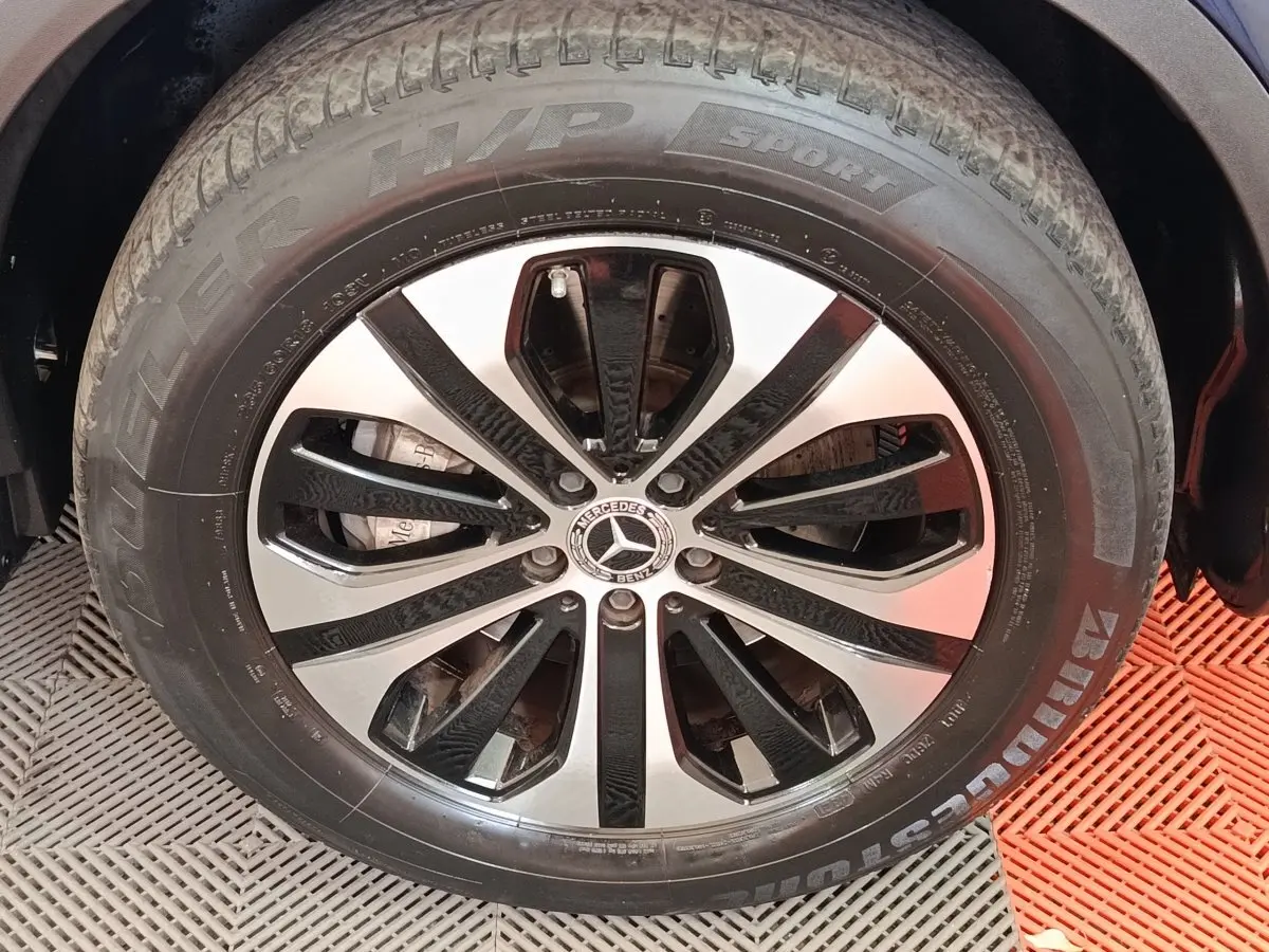 Gros plan sur la jante alliage noir et argent avec logo Mercedes d’un Mercedes GLC bleu, vue latérale.