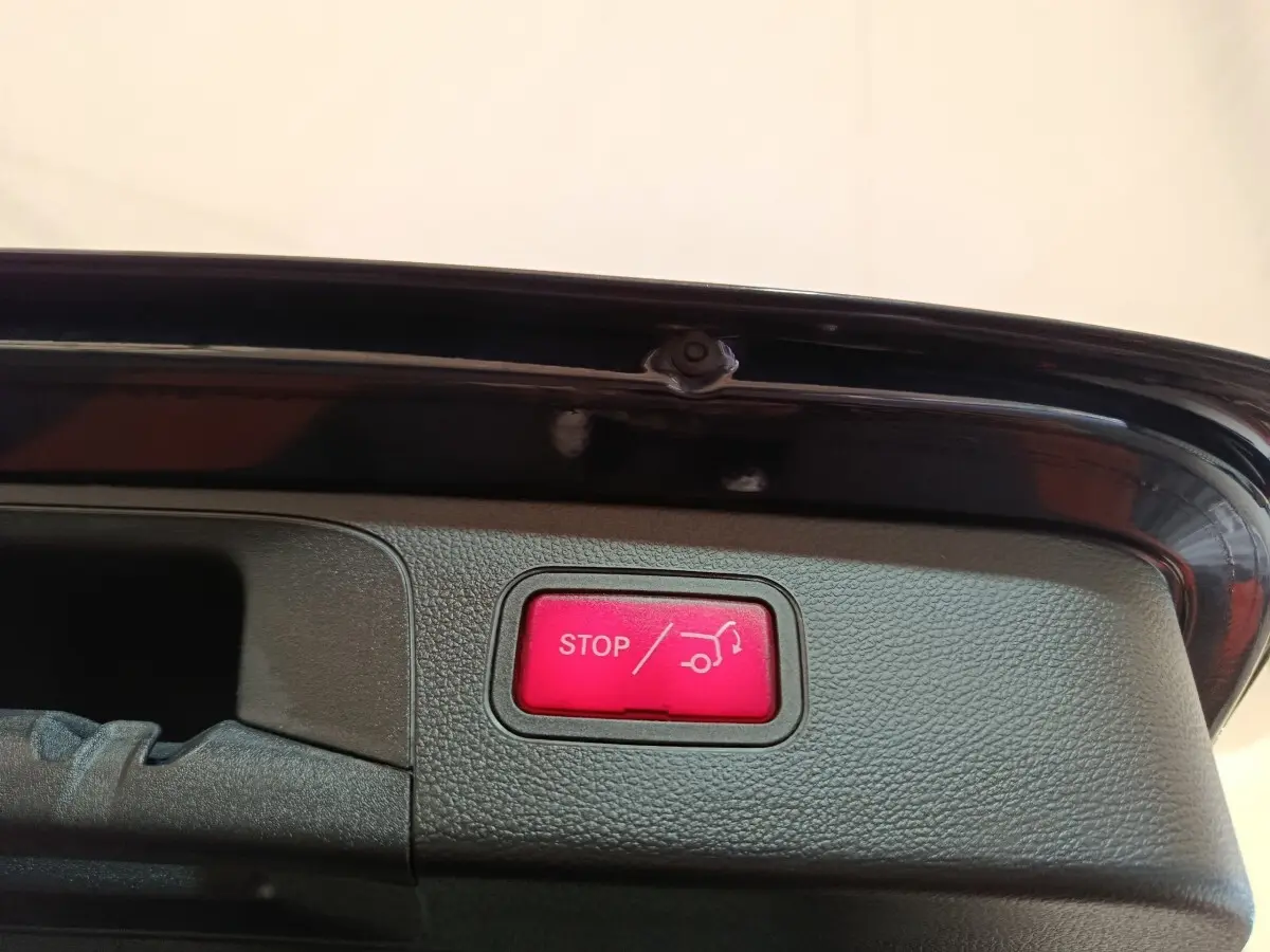 Bouton rouge stop ouverture coffre sur la partie intérieure du hayon d’un Mercedes GLC bleu hybride rechargeable.