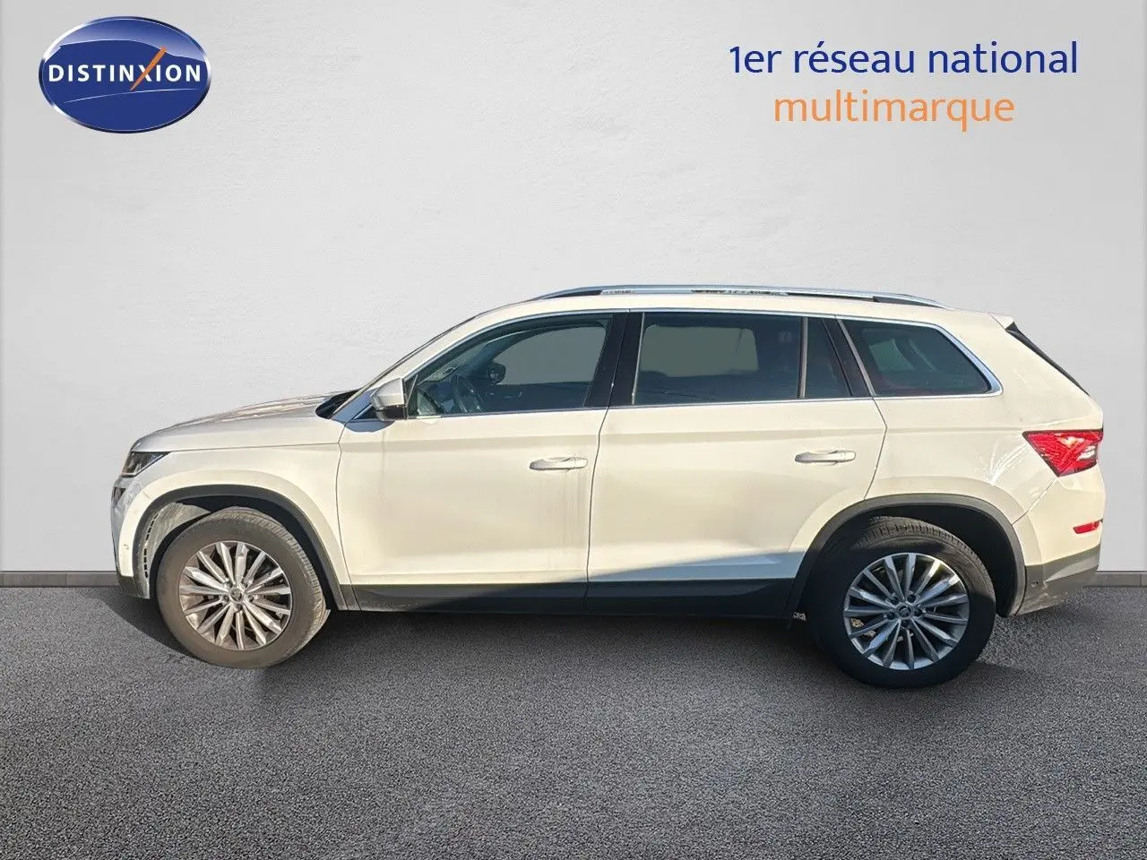 Profil côté gauche d'un SUV Skoda Kodiaq blanc 2018 avec jantes alliage et vitres teintées sur fond neutre.