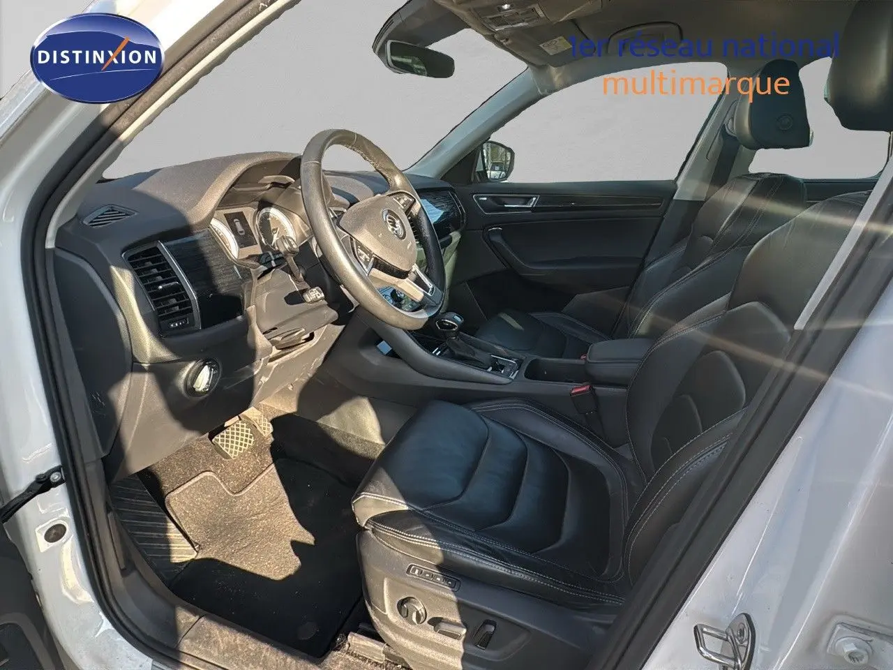 Intérieur noir cuir du Skoda Kodiaq blanc 2018, vue côté gauche sur le poste de conduite et les sièges avant.