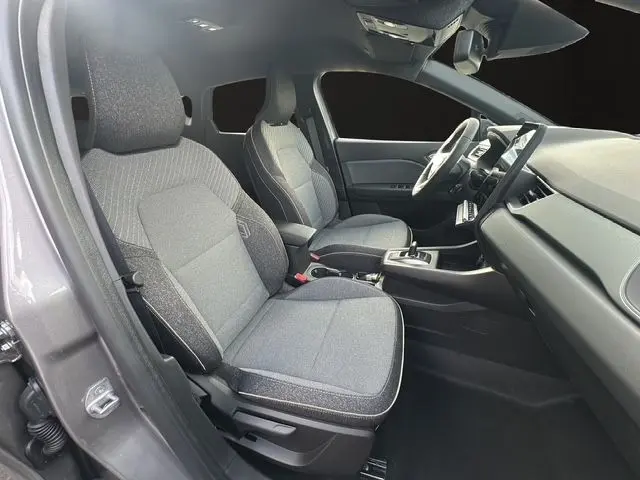 Vue intérieure côté conducteur du Renault Captur 2025 gris Cassiopée, montrant les sièges tissu gris et le tableau de bord moderne.
