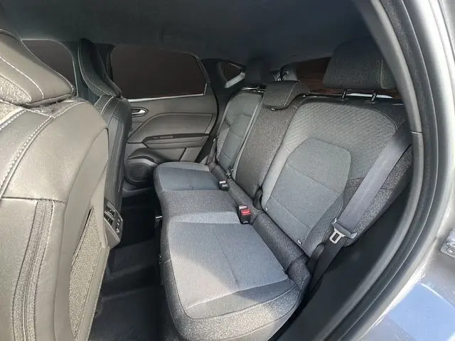 Vue intérieure arrière droite du Renault Captur 2025, sièges tissu gris et ceintures de sécurité visibles.