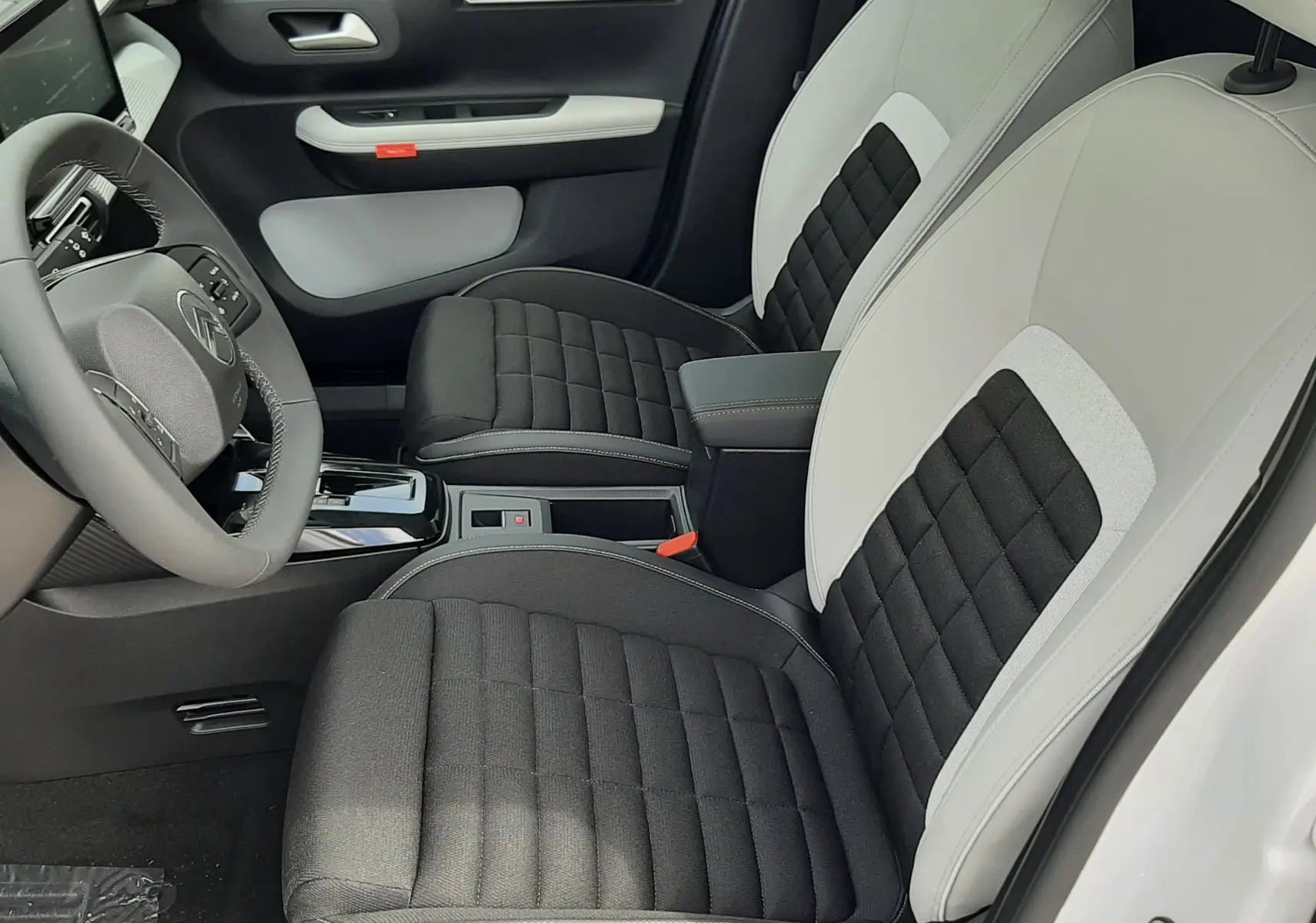 Intérieur avant droit de la Citroën C3 Aircross blanc banquise avec sièges bicolores noir et blanc, volant et console centrale visibles.