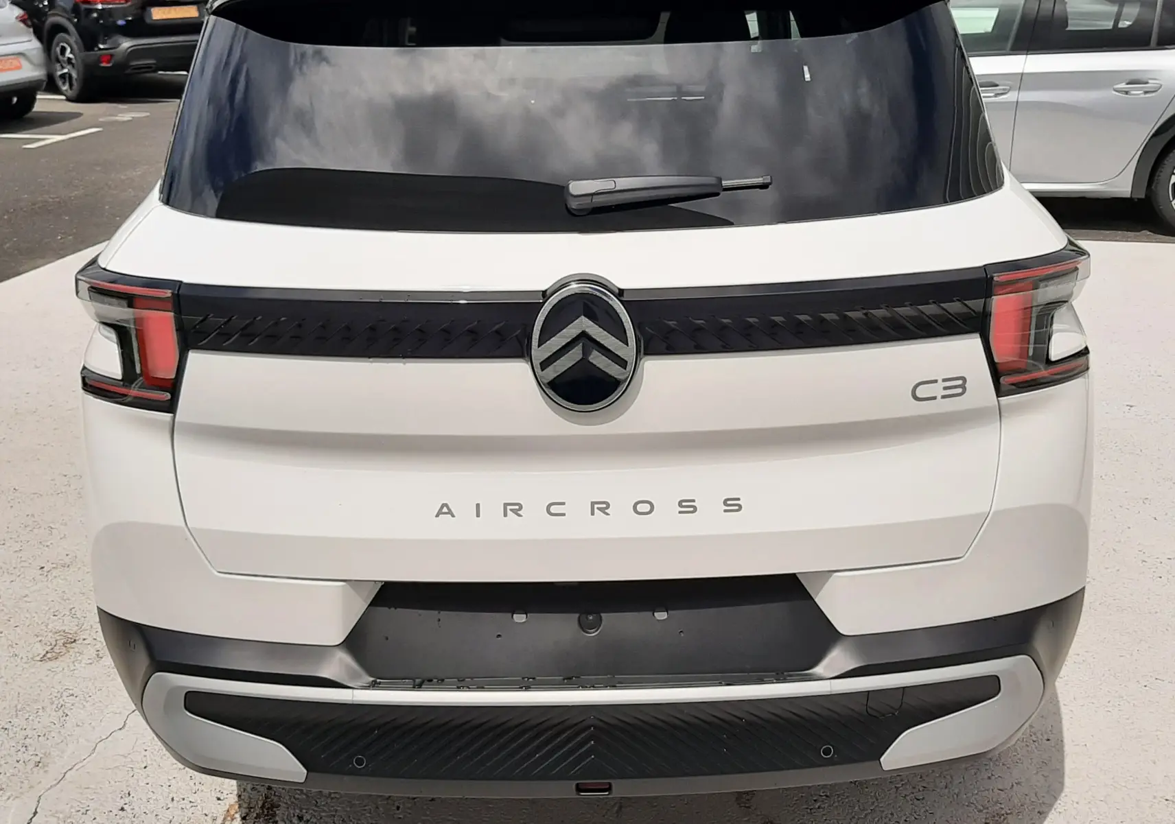 Vue arrière d'une Citroën C3 Aircross blanc banquise avec toit noir, feux arrière LED et logo central distinctif.