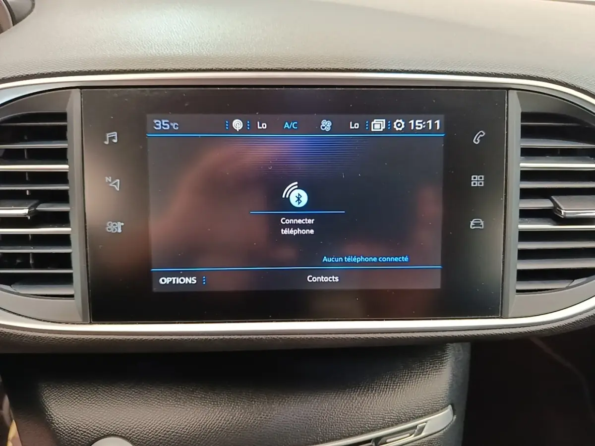 Écran tactile central du tableau de bord de la Peugeot 308 blanc, affichant la connexion Bluetooth au téléphone.