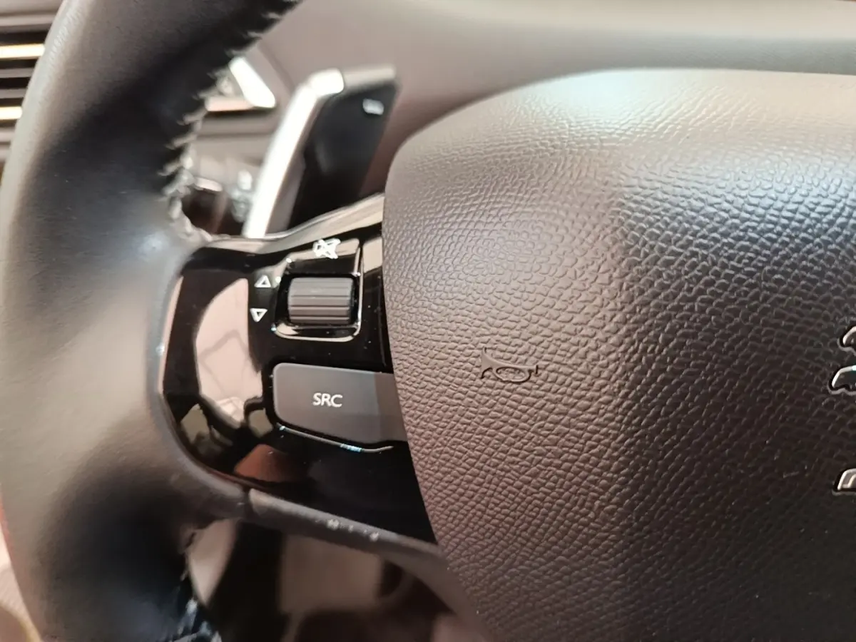 Gros plan sur le volant cuir noir de la Peugeot 308 2020, avec commandes audio intégrées côté gauche.
