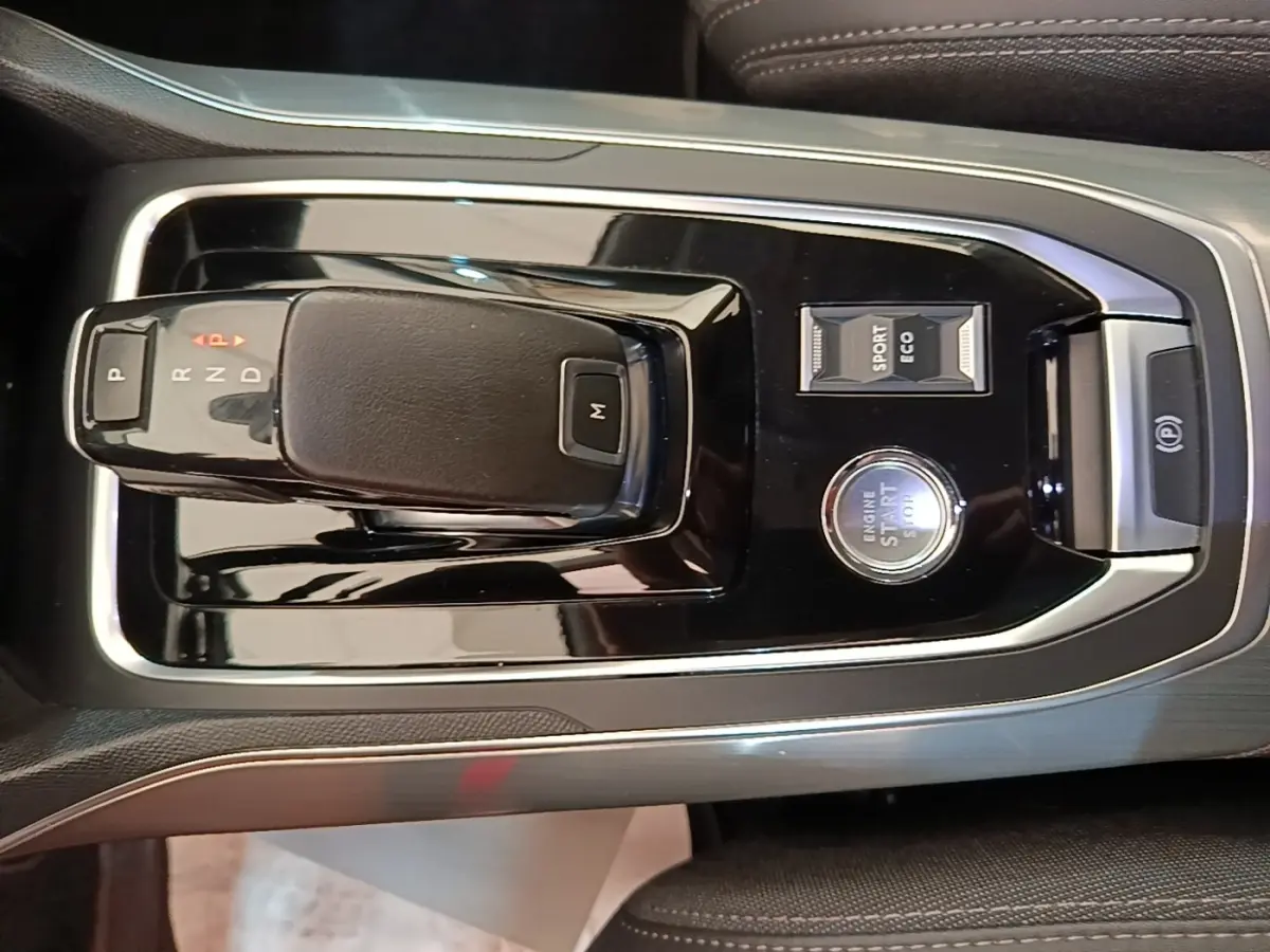 Vue rapprochée de la console centrale noire brillante avec levier de boîte auto et bouton start/stop de la Peugeot 308.