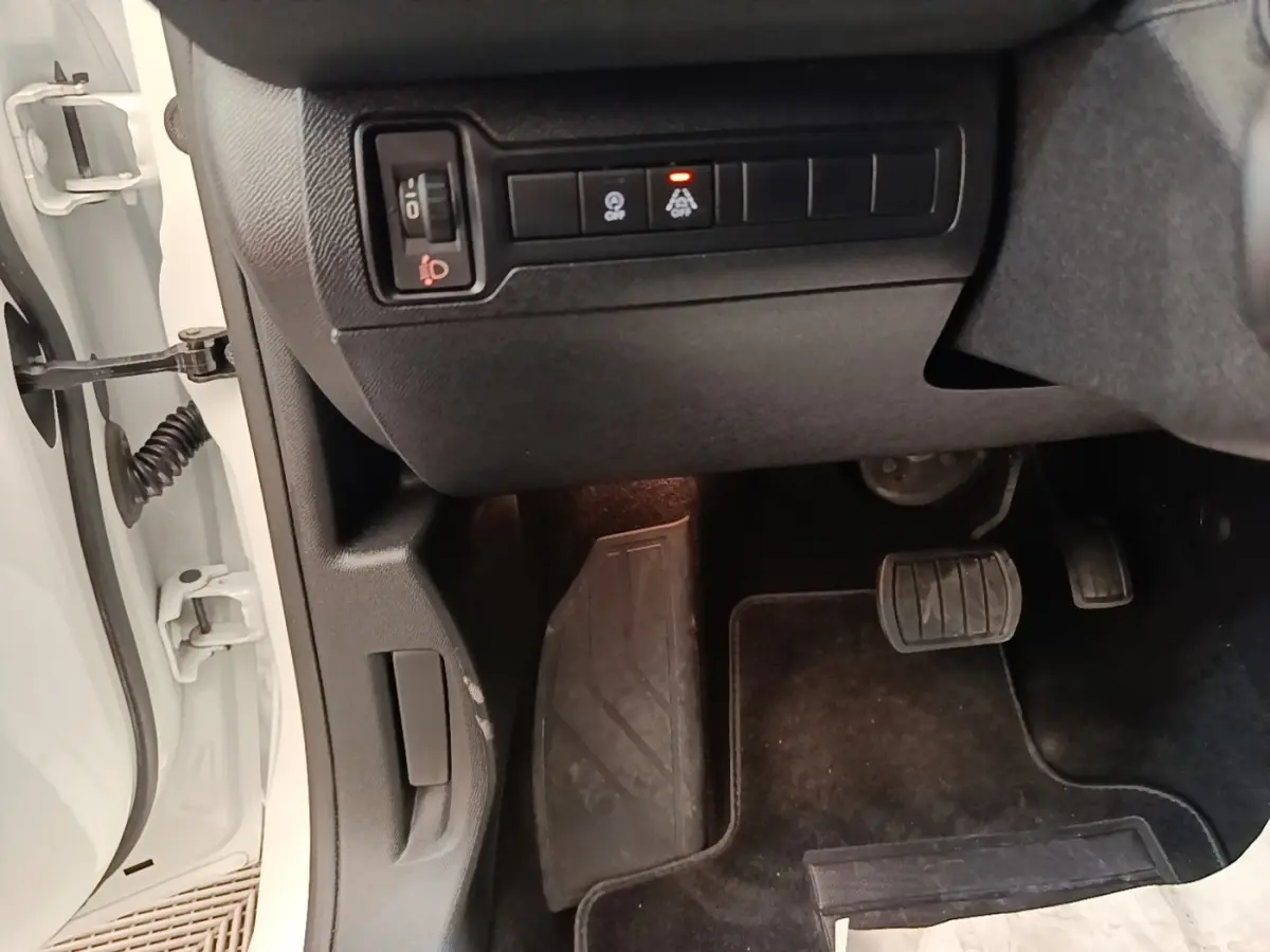 Vue intérieure côté conducteur de la Peugeot 308 blanche, montrant les pédales et commandes sous le tableau de bord.