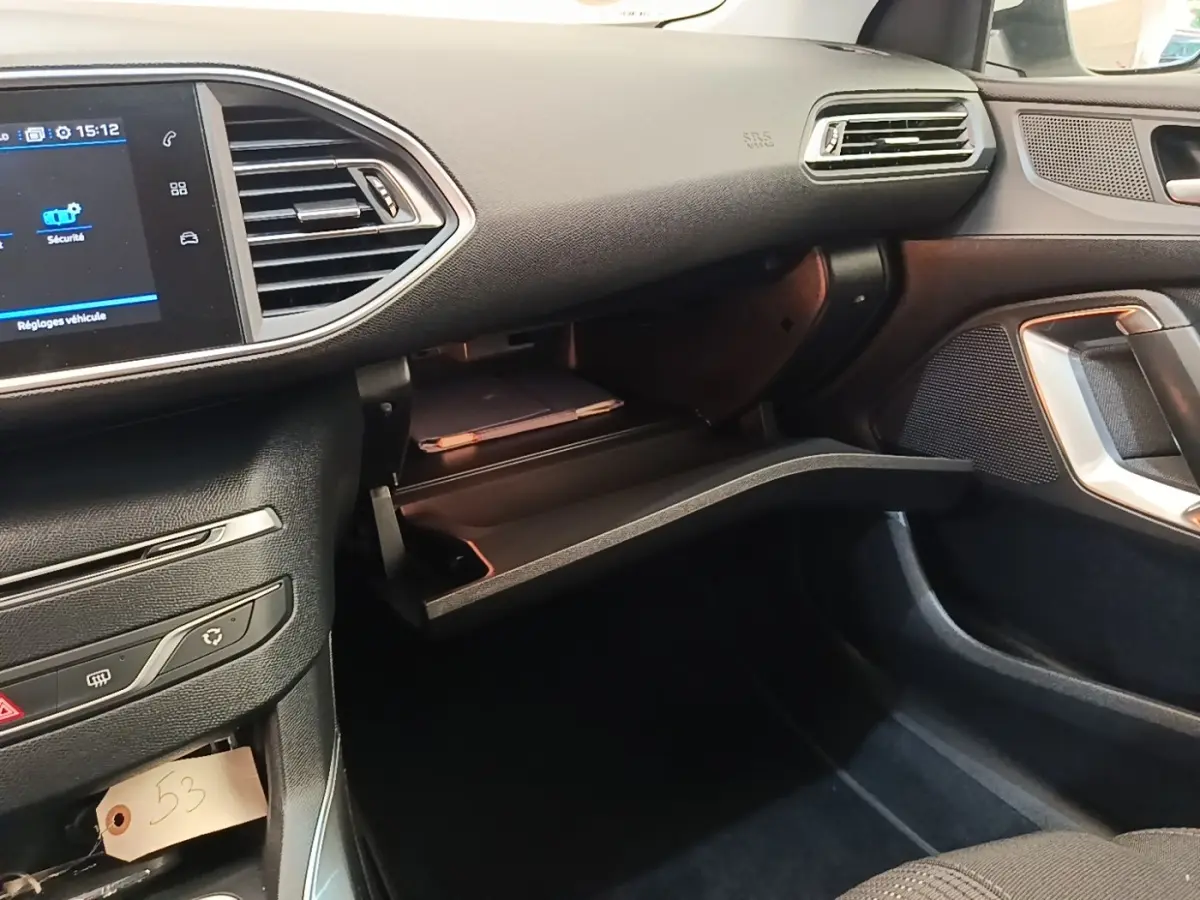 Vue intérieure côté passager de la Peugeot 308 2020 avec boîte à gants ouverte et écran tactile visible.