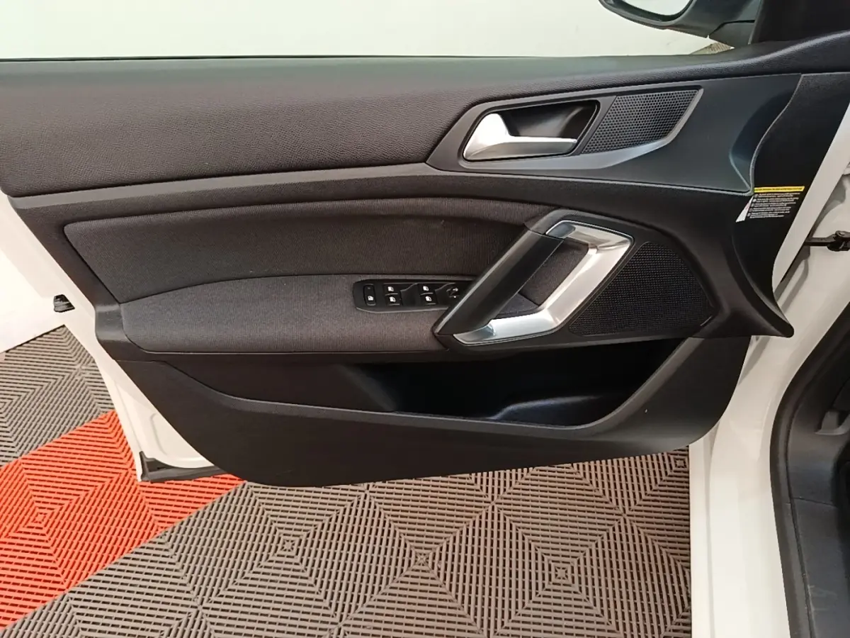 Vue rapprochée de la porte avant gauche blanche d’une Peugeot 308 2020 avec garniture noire et commandes de vitres.