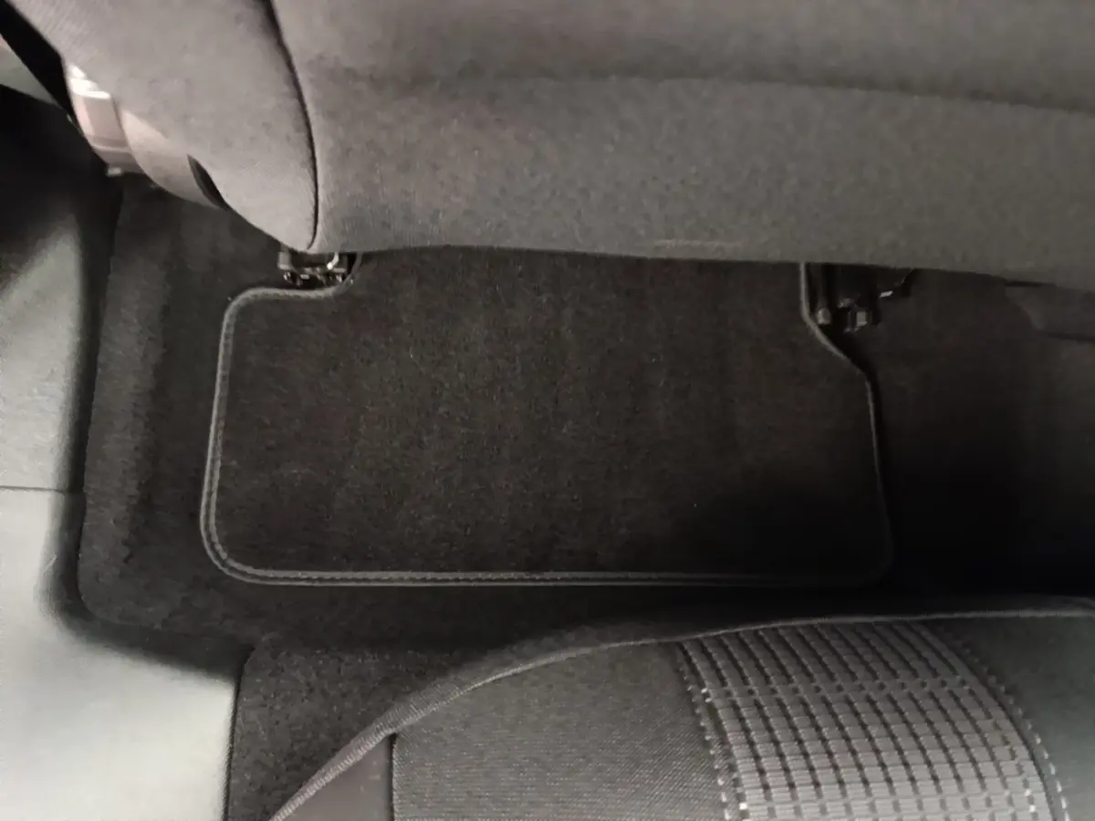 Vue rapprochée du tapis de sol arrière côté gauche de la Peugeot 308 blanche, avec siège tissu gris visible.