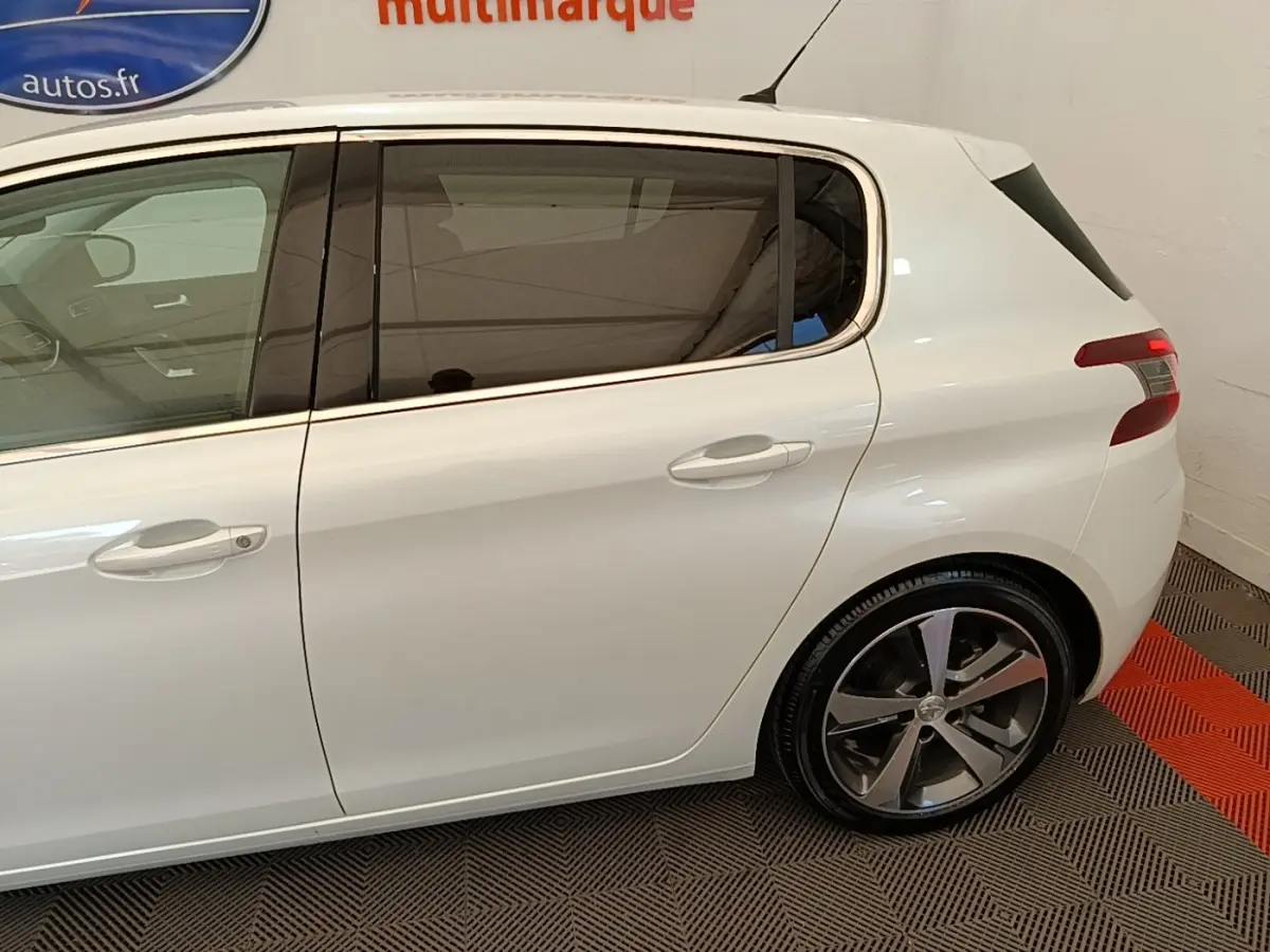 Profil côté gauche de la Peugeot 308 blanche, mettant en valeur les vitres teintées et les jantes alliage.