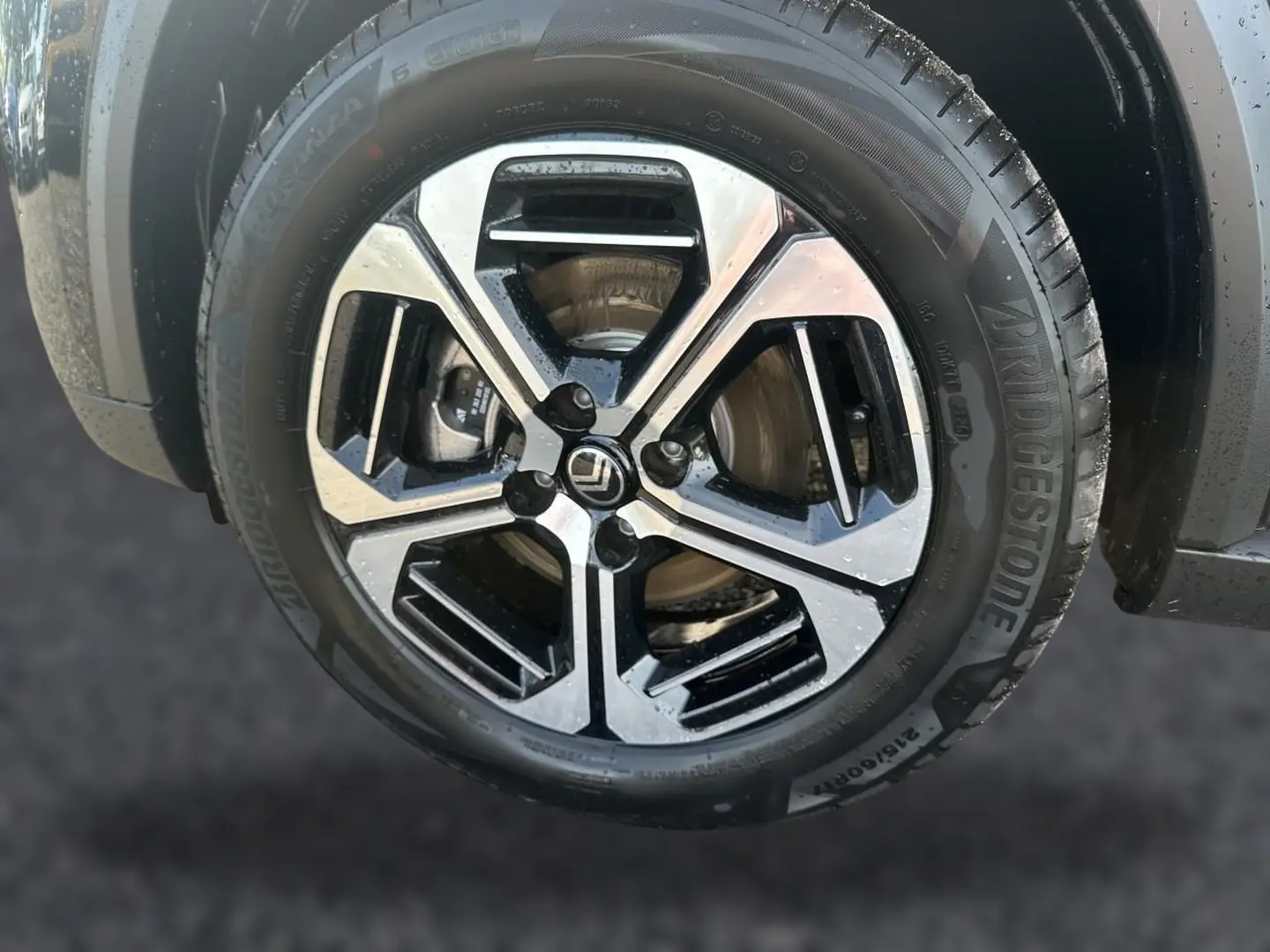 Gros plan sur la jante alu noire et argentée d'une Citroën C3 Aircross noire, avec pneu Bridgestone visible.