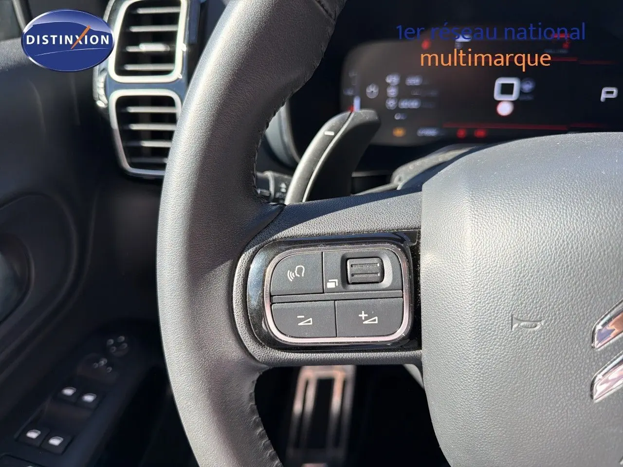 Gros plan sur le volant cuir du Citroën C5 Aircross blanc nacré, avec commandes audio intégrées à gauche.