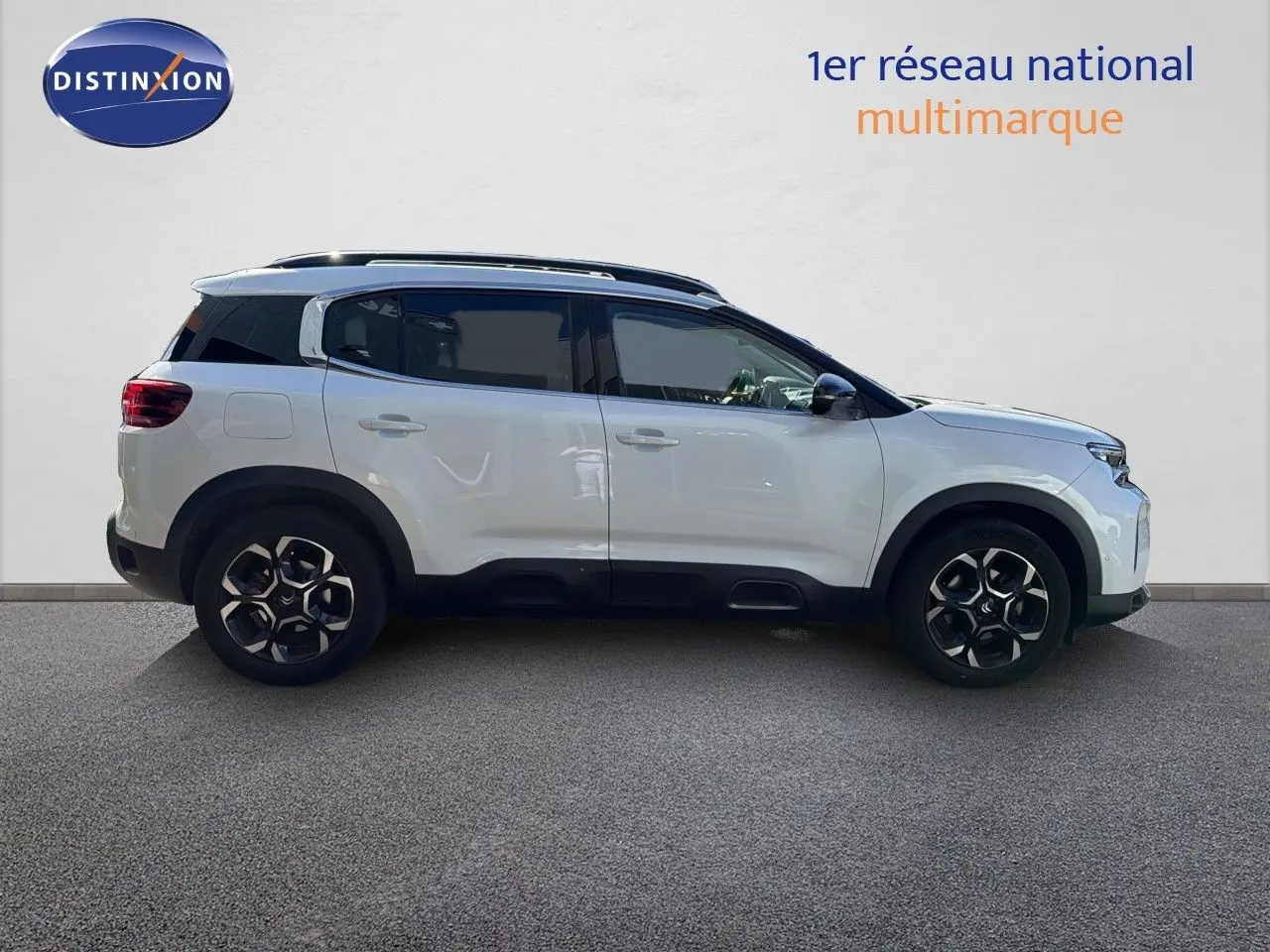 Profil droit d'un Citroën C5 Aircross blanc nacré 2023 avec toit noir et jantes alliage bicolores.
