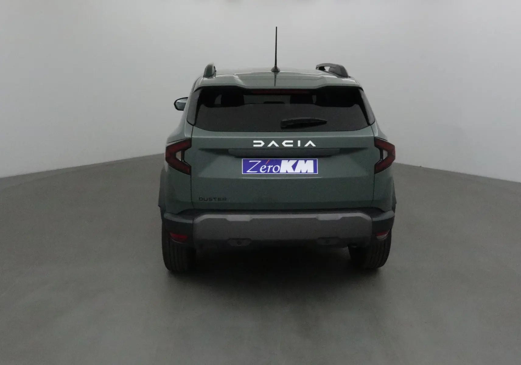 Vue arrière d'un Dacia Duster 2025 kaki lichen avec logo DACIA lumineux et vitres arrière teintées.