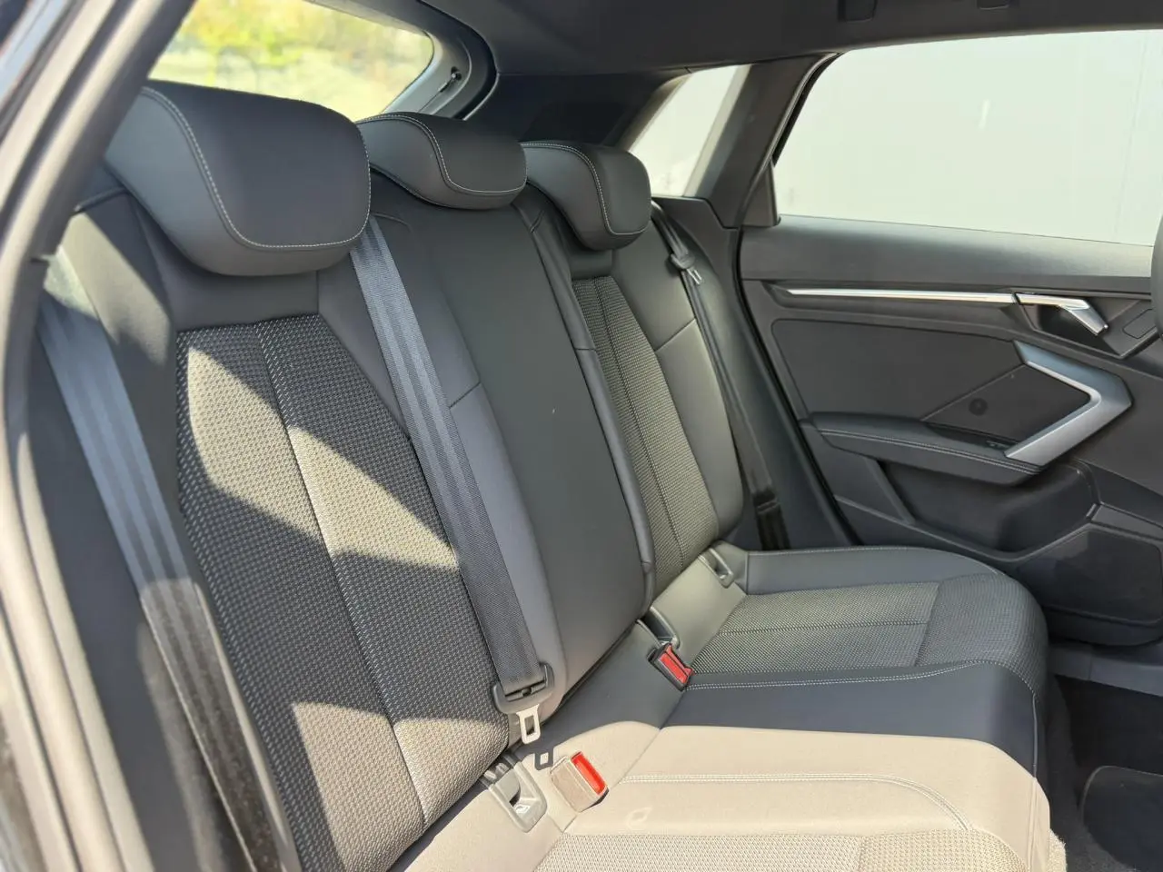 Vue intérieure côté droit des sièges arrière en tissu noir avec ceinture de sécurité et garnitures modernes sur une Audi A3 Sportback 2025.