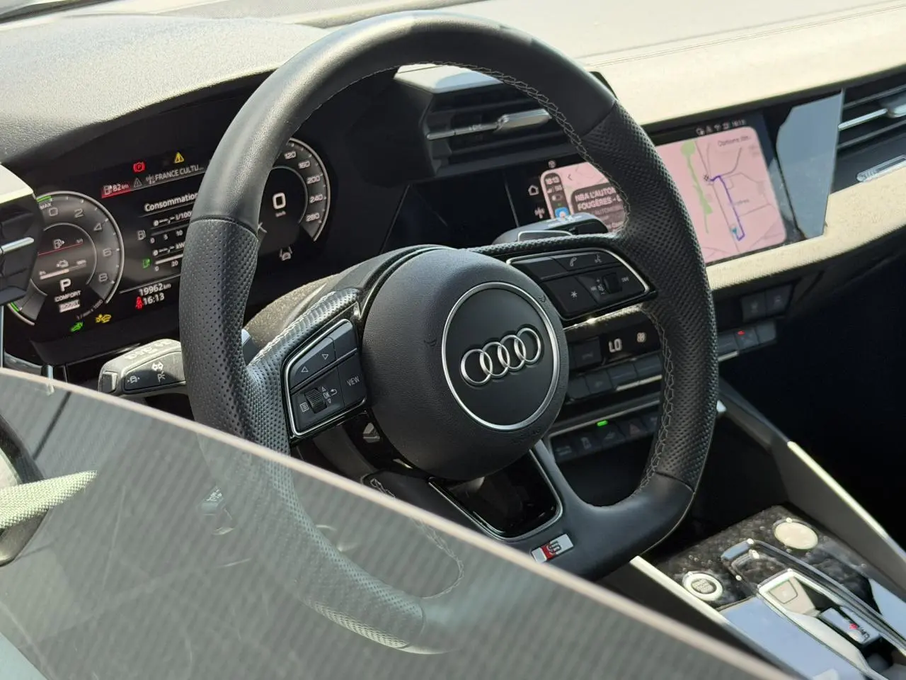 Vue rapprochée du volant sport en cuir perforé avec logo Audi et tableau de bord numérique d'une Audi A3 Sportback 2025.