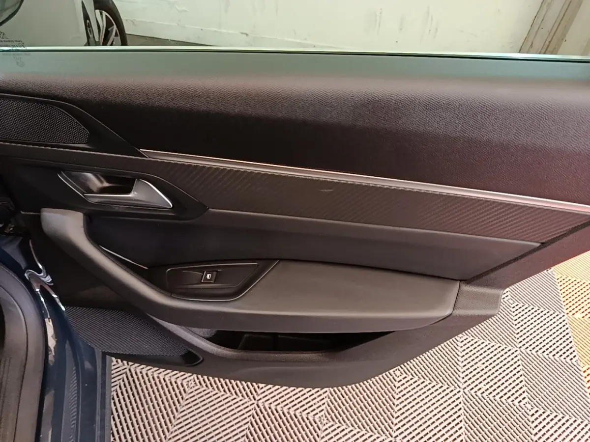 Vue rapprochée de la porte avant gauche de la Peugeot 508 gris foncé, montrant la poignée et les commandes de vitre.