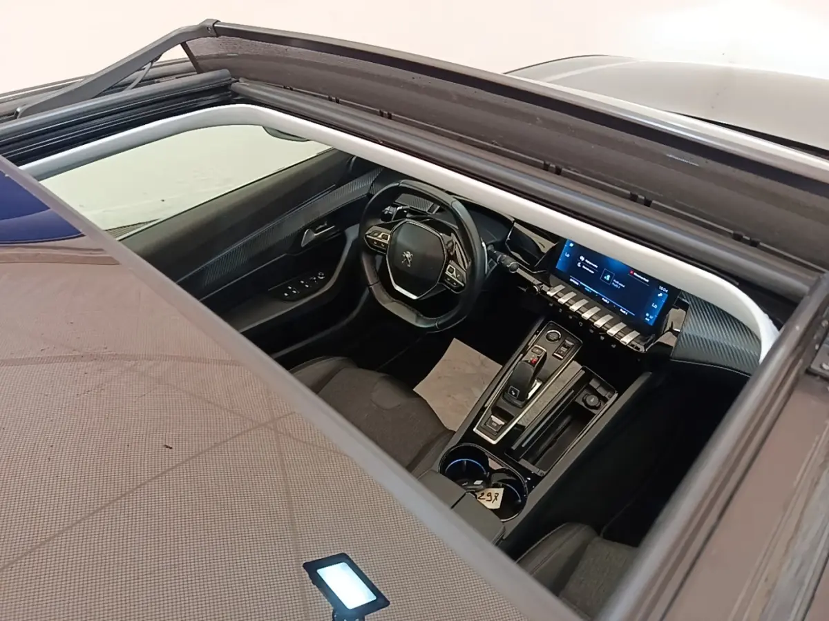 Vue plongeante sur l’intérieur noir de la Peugeot 508 gris foncé, avec tableau de bord digital et toit ouvrant.