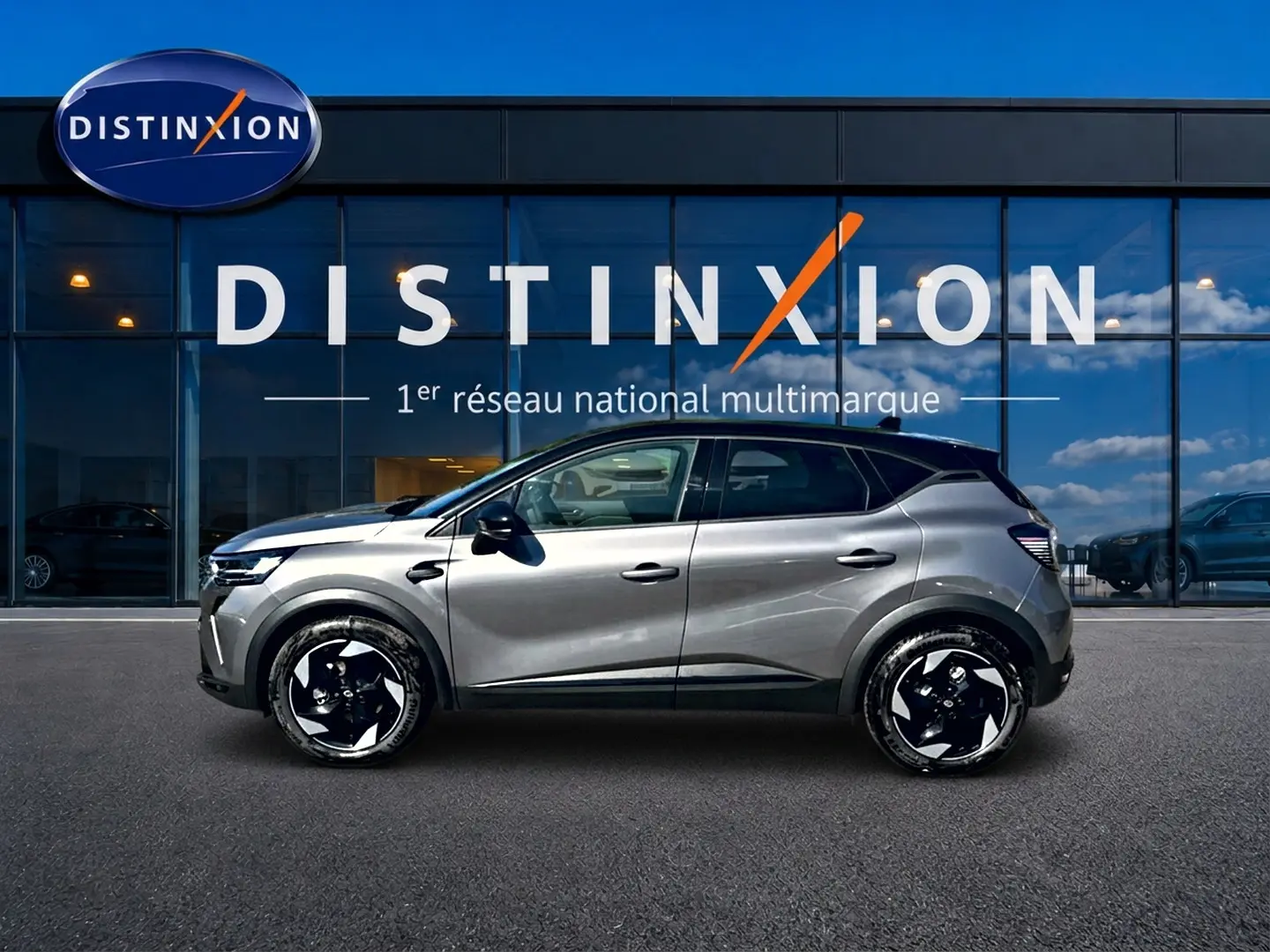Renault Captur gris Cassiopée vu de profil côté gauche devant une vitrine Distinxion, jantes noires et blanches.