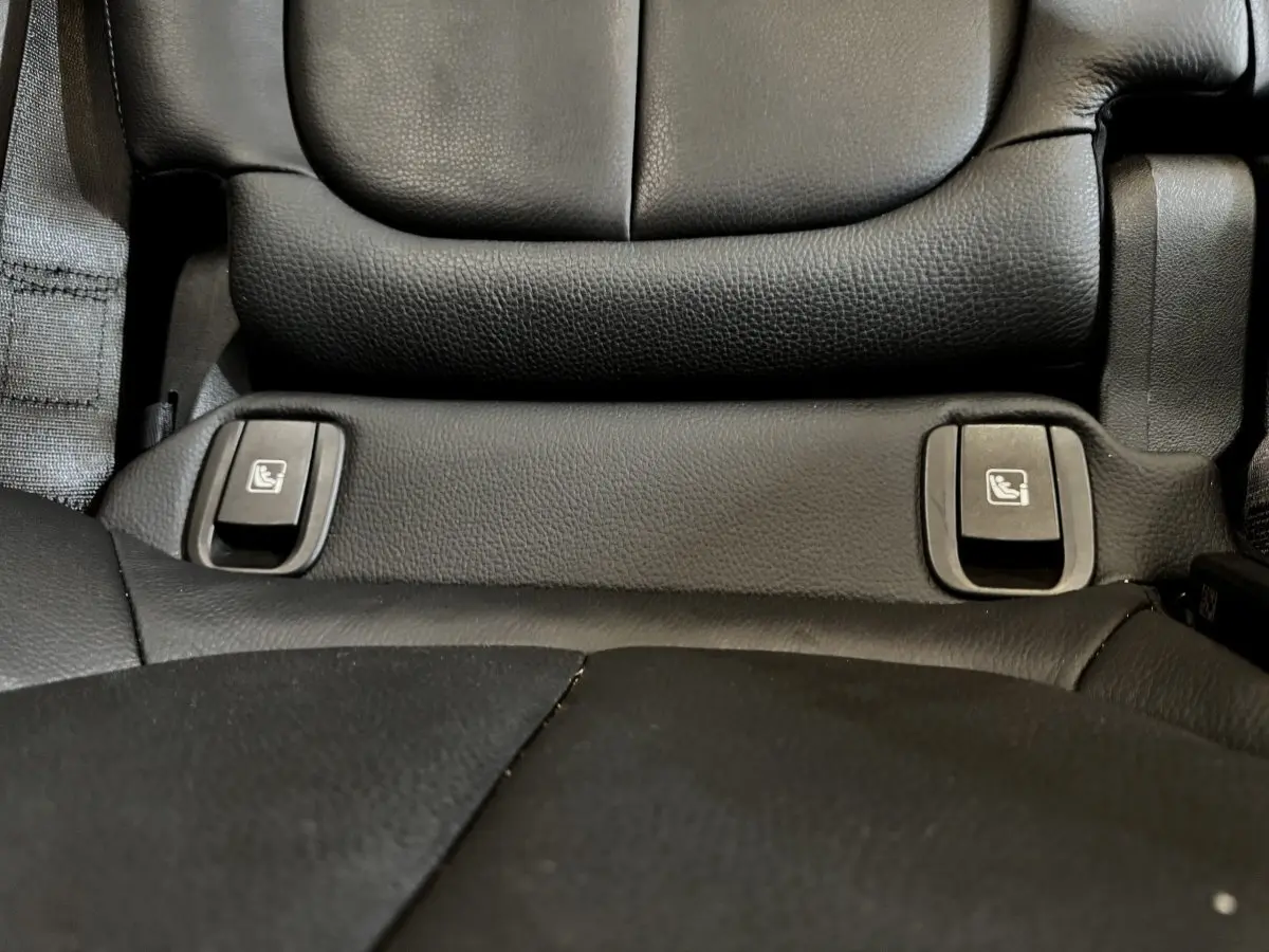 Détail des commandes de rabattement des sièges arrière en cuir noir dans une BMW X2 blanche hybride rechargeable.