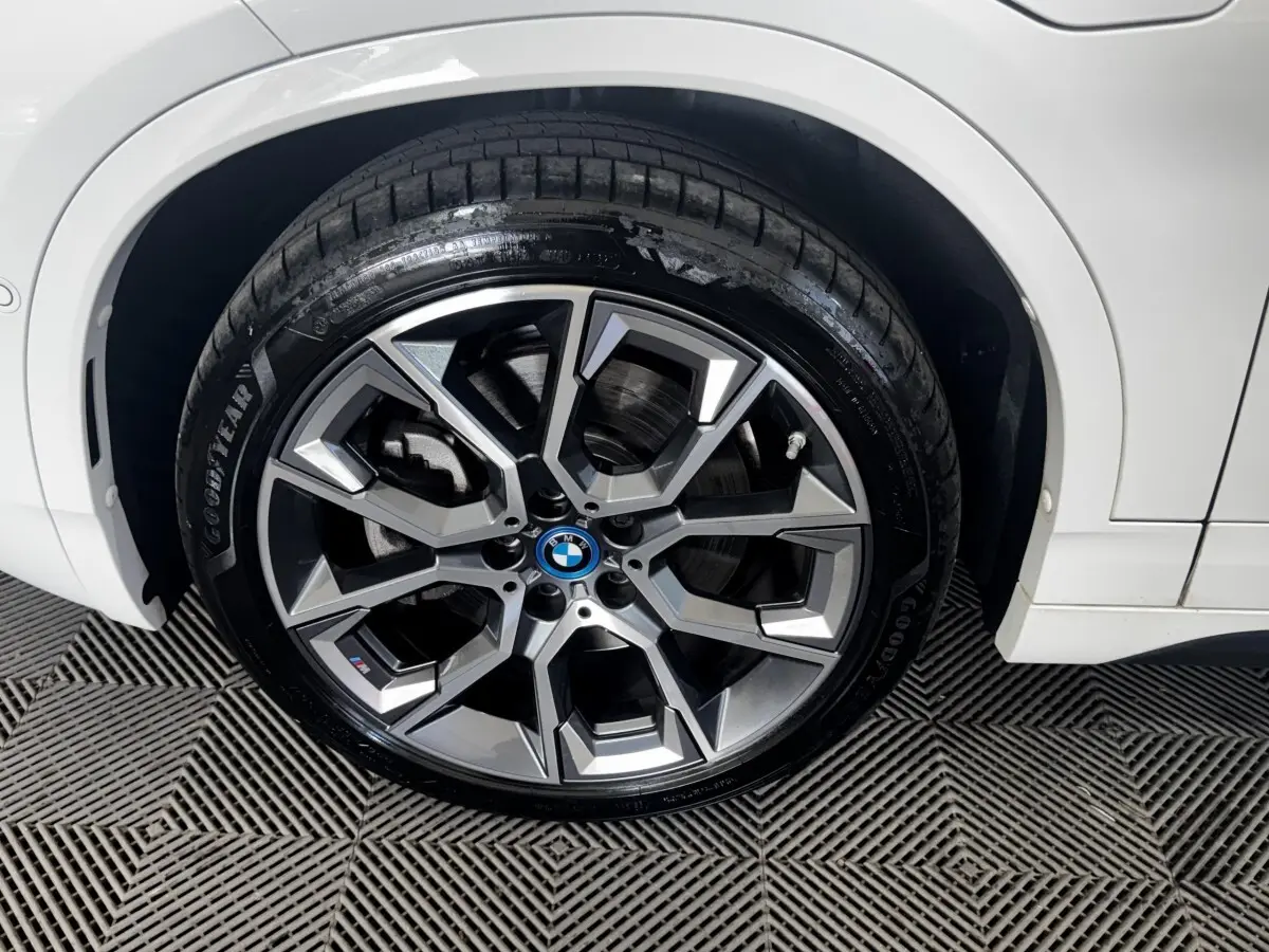 Gros plan sur la roue avant droite d’un BMW X2 blanc avec jante alliage M Sport à design géométrique.
