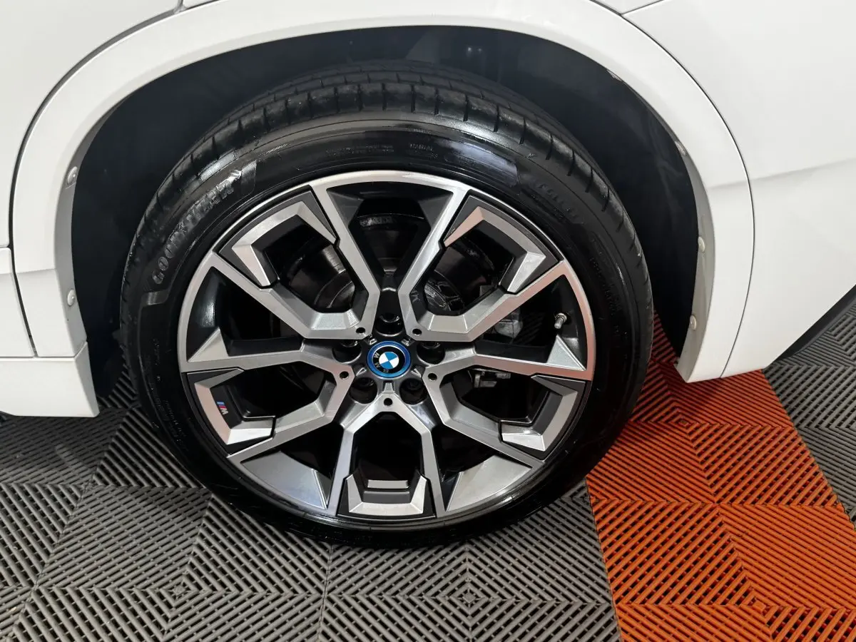 Gros plan sur la roue avant droite d’un BMW X2 blanc avec jante alliage M Sport au design géométrique.